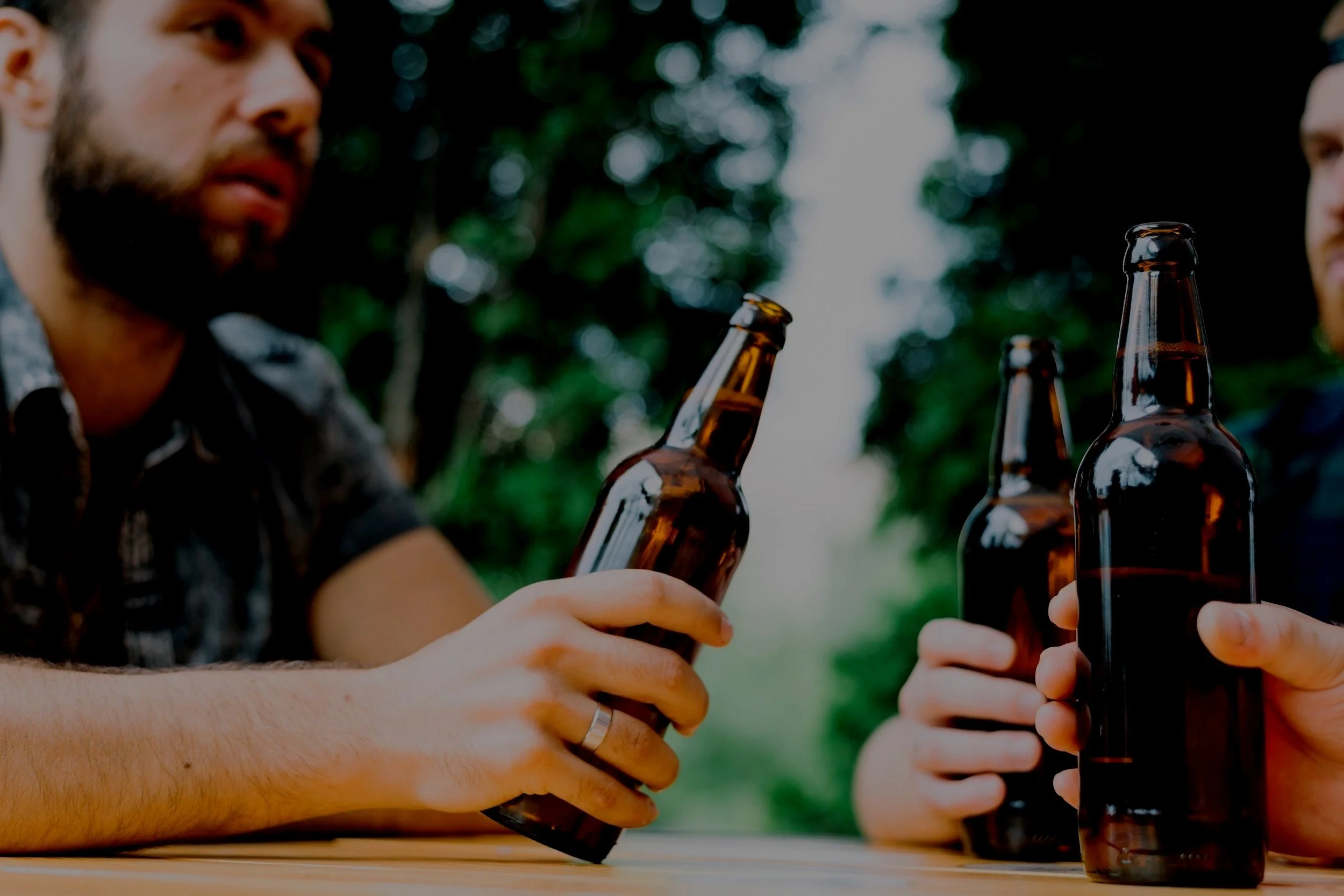 man-sitting-with-his-friend-holding-brown-beer-bottle-outdoors.jpg