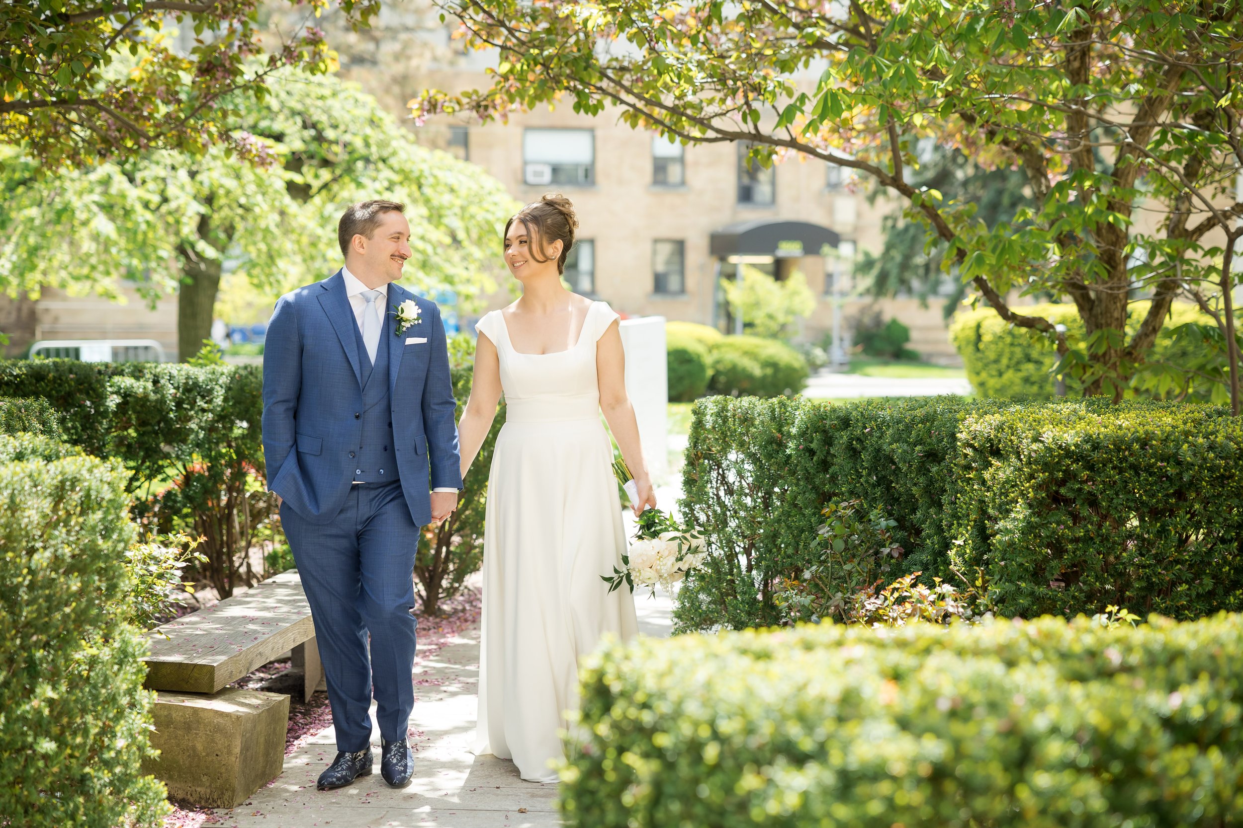 bride and groom walking through tree path