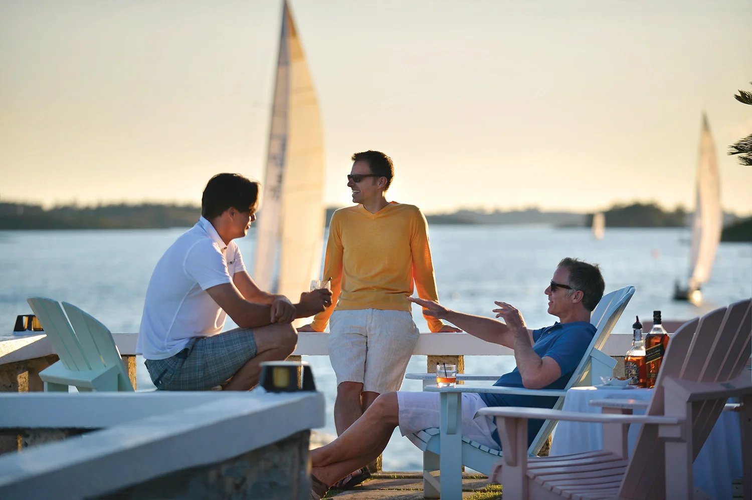 Friends having drinks by ocean watching a sailing race.