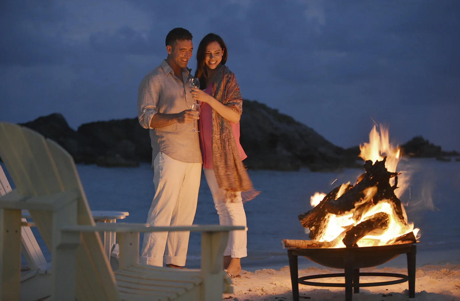Couple by fire on beach.