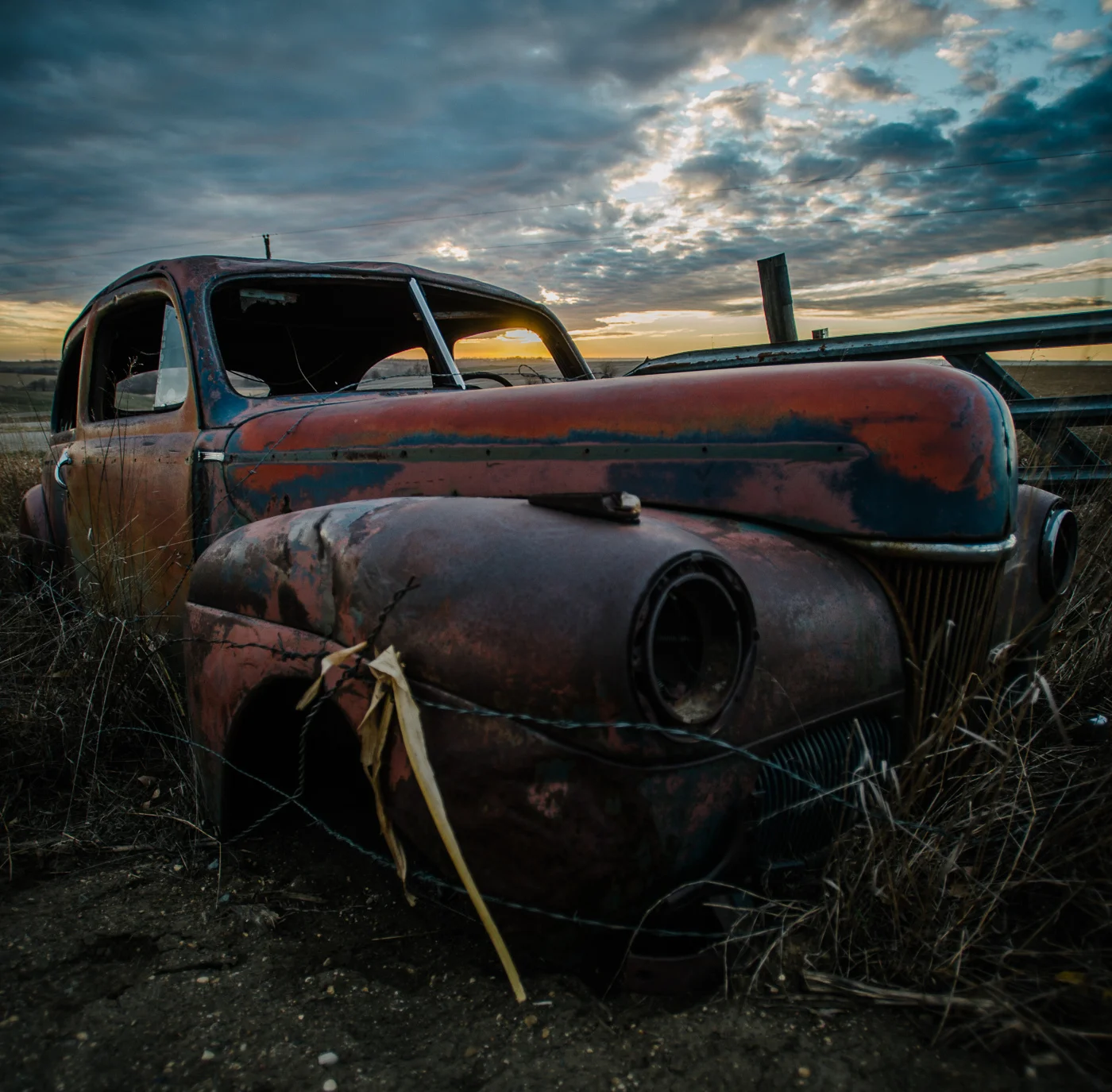 An abandoned car rests on the open prairie ground of northwest Iowa.