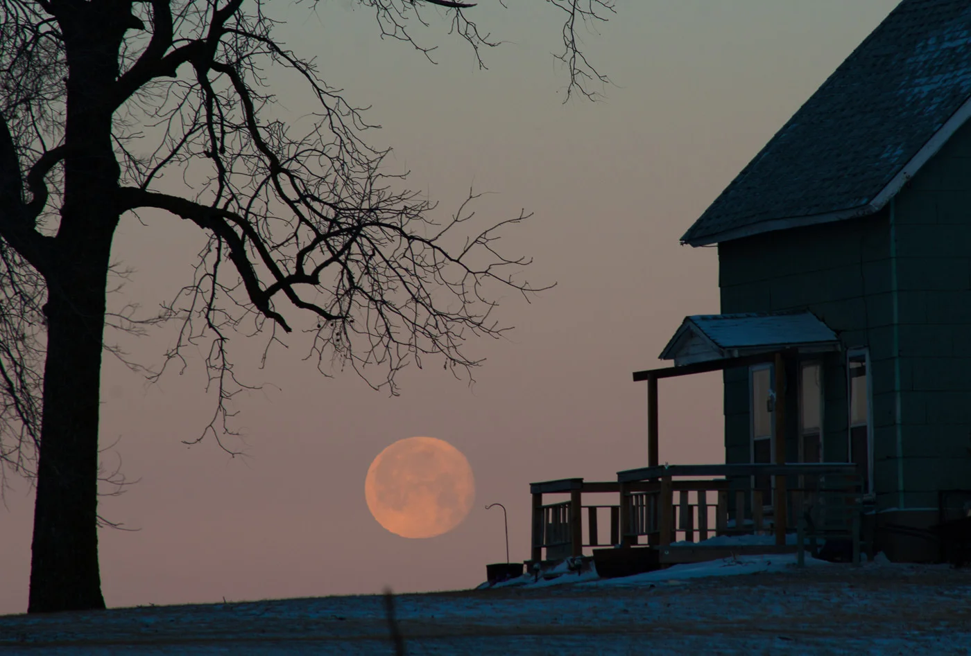 A full moon retires into the horizon as the sun rises on a winter day near Granger, Iowa.