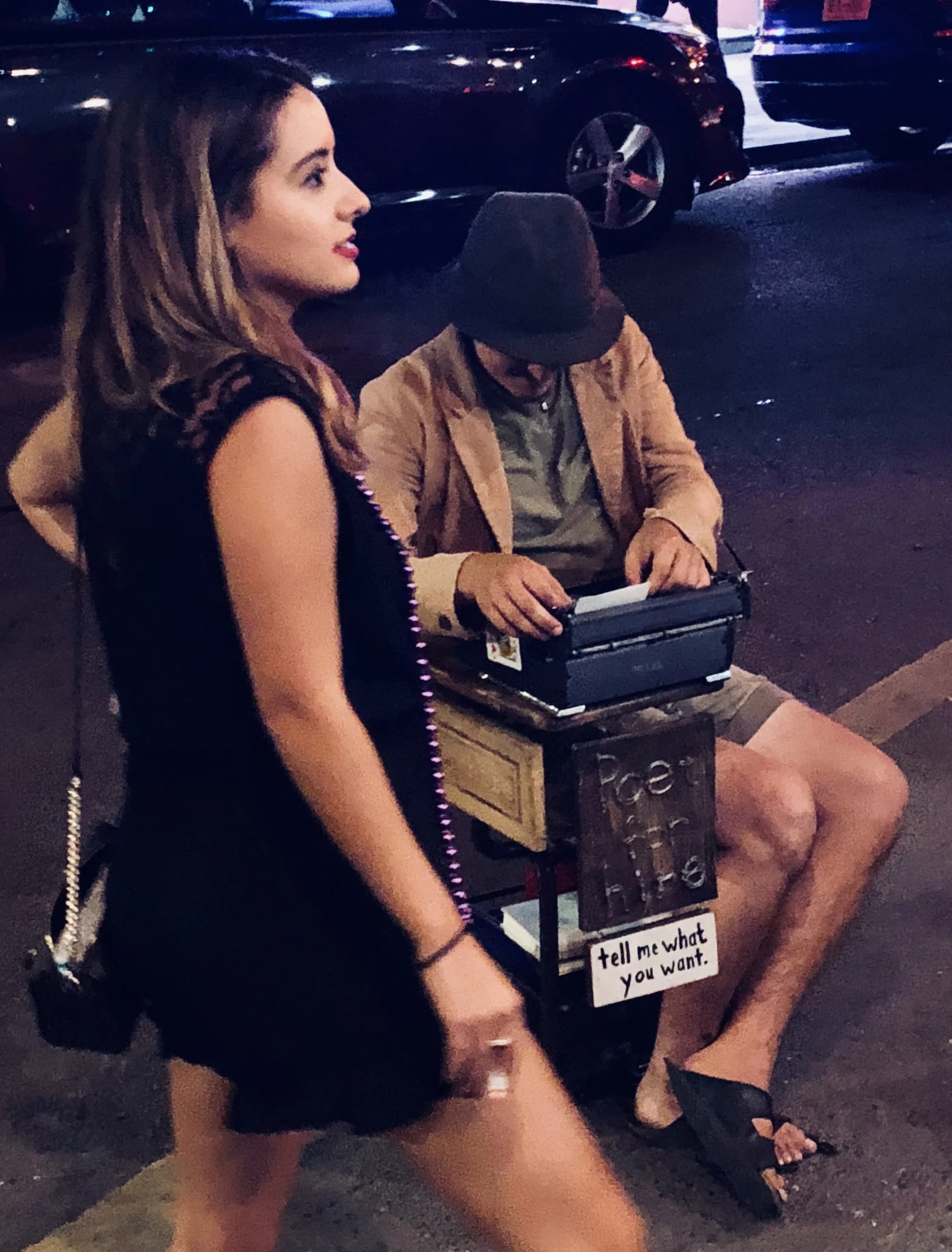A street poet prepares for inspiration as a woman enjoys a smoke and waits for friends on Frenchmen Street in New Orleans.