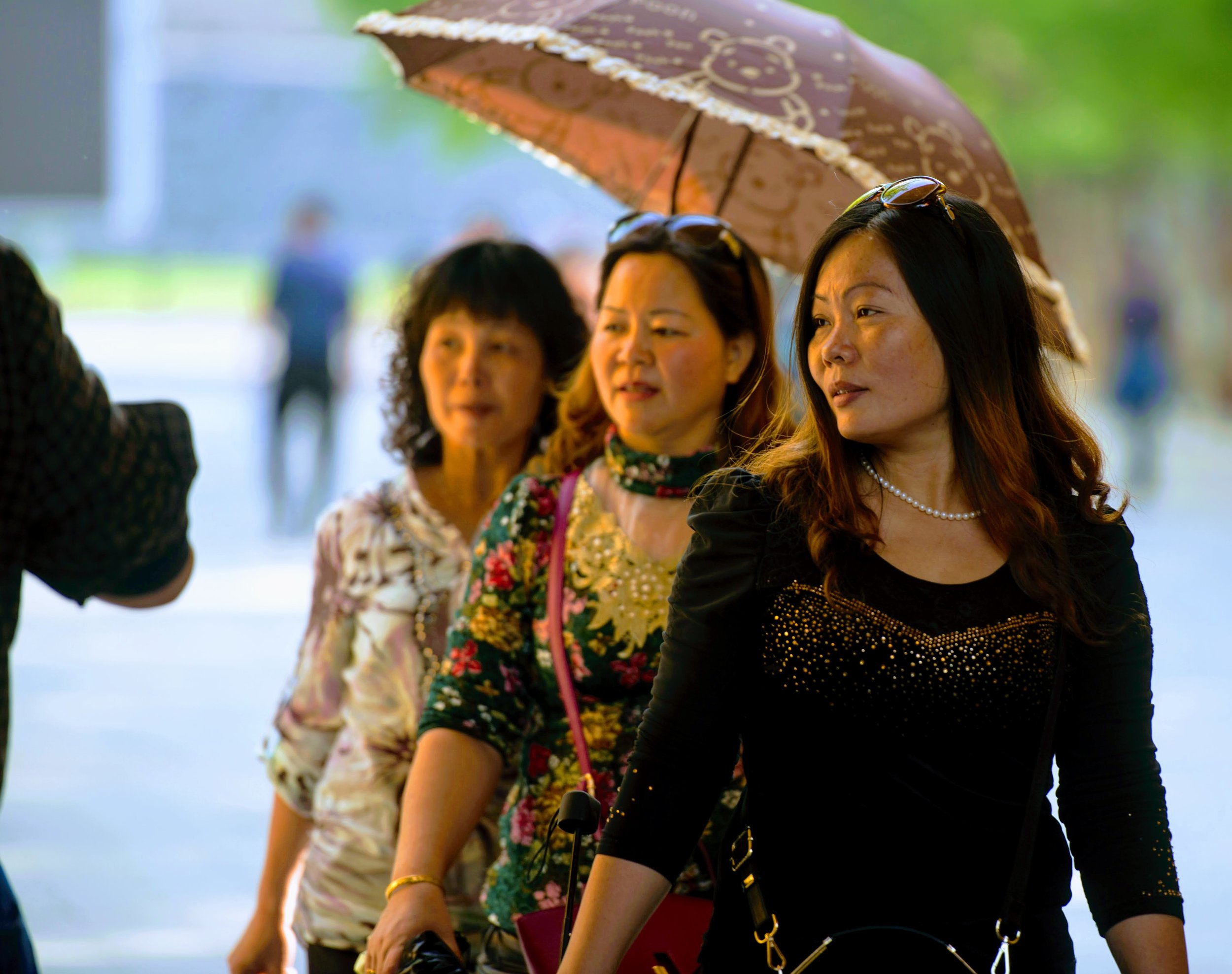  Chinese women walk past a street musician while taking a stroll in Beijing, China.   