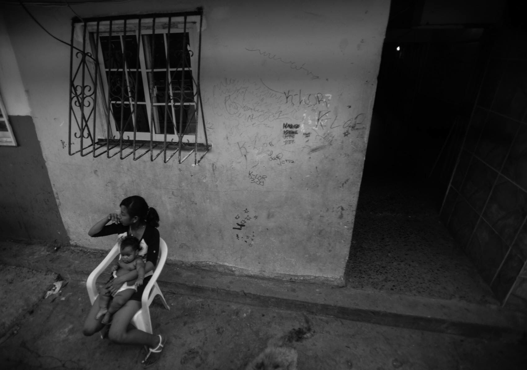  A girl holds an infant while watching traffic flow by in the old town area of Panama City, Panama.   