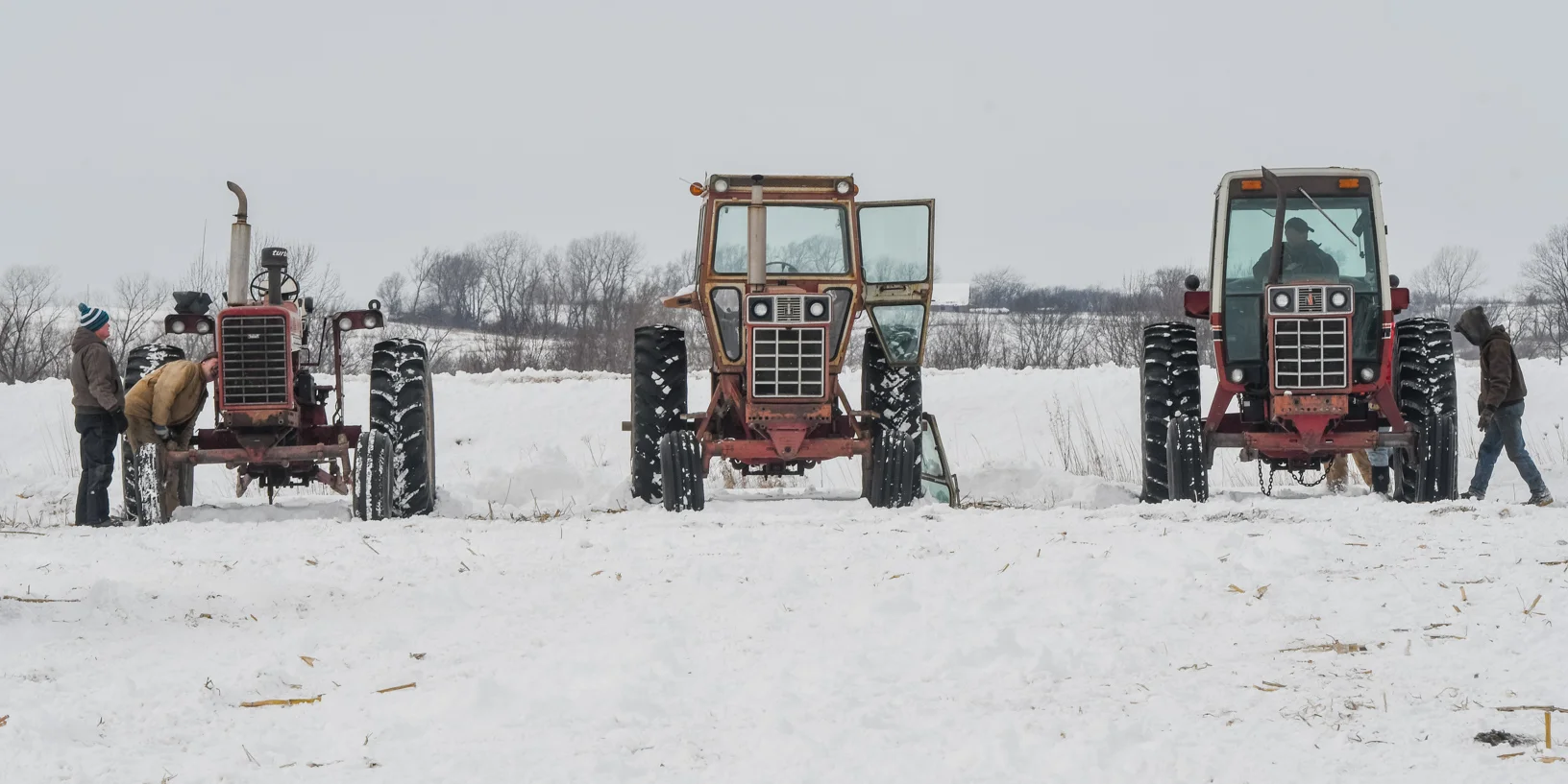 Men look over tractors before the auctioneer sells them to the highest bidder.