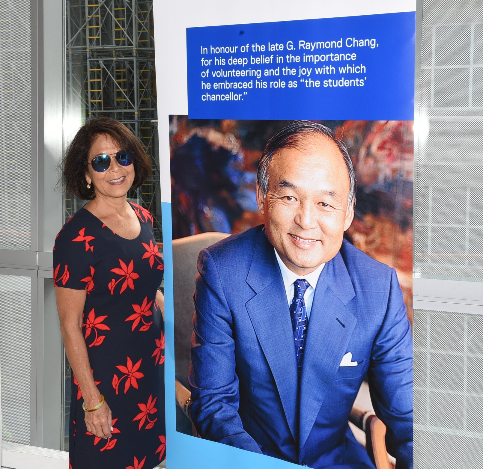 Donette Chin-Loy Chang standing next to a portrait of her late husband Raymond Chang
