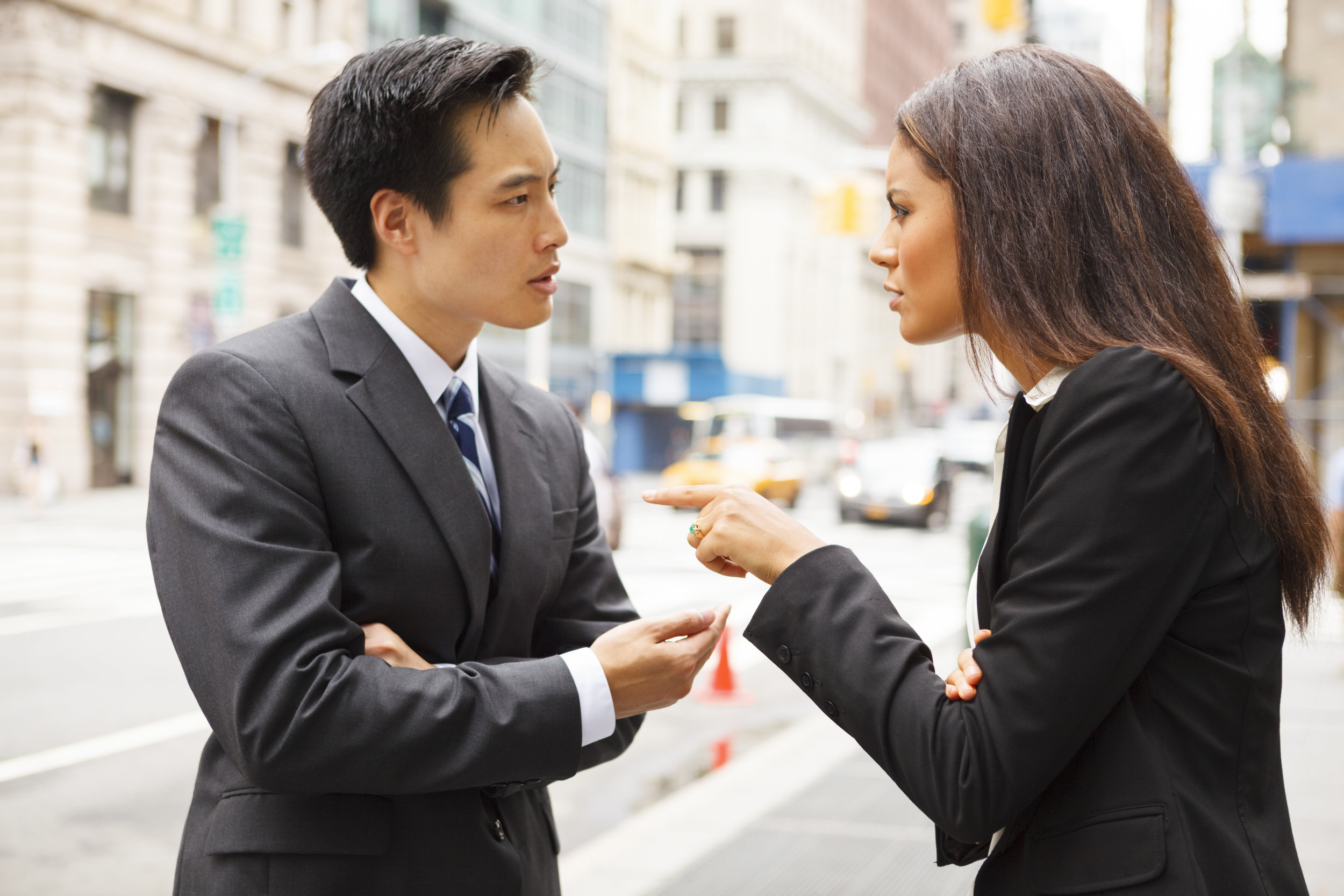 A man and a woman arguing on a city street.