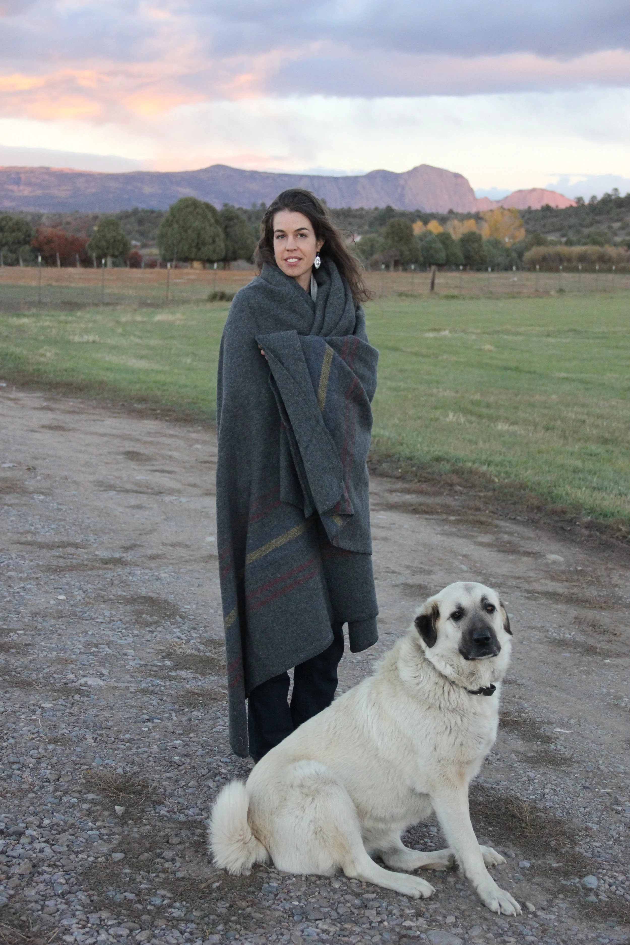 Lara Manzanares and Osa, one of the flock's guard dogs, stay warm on the ranch.