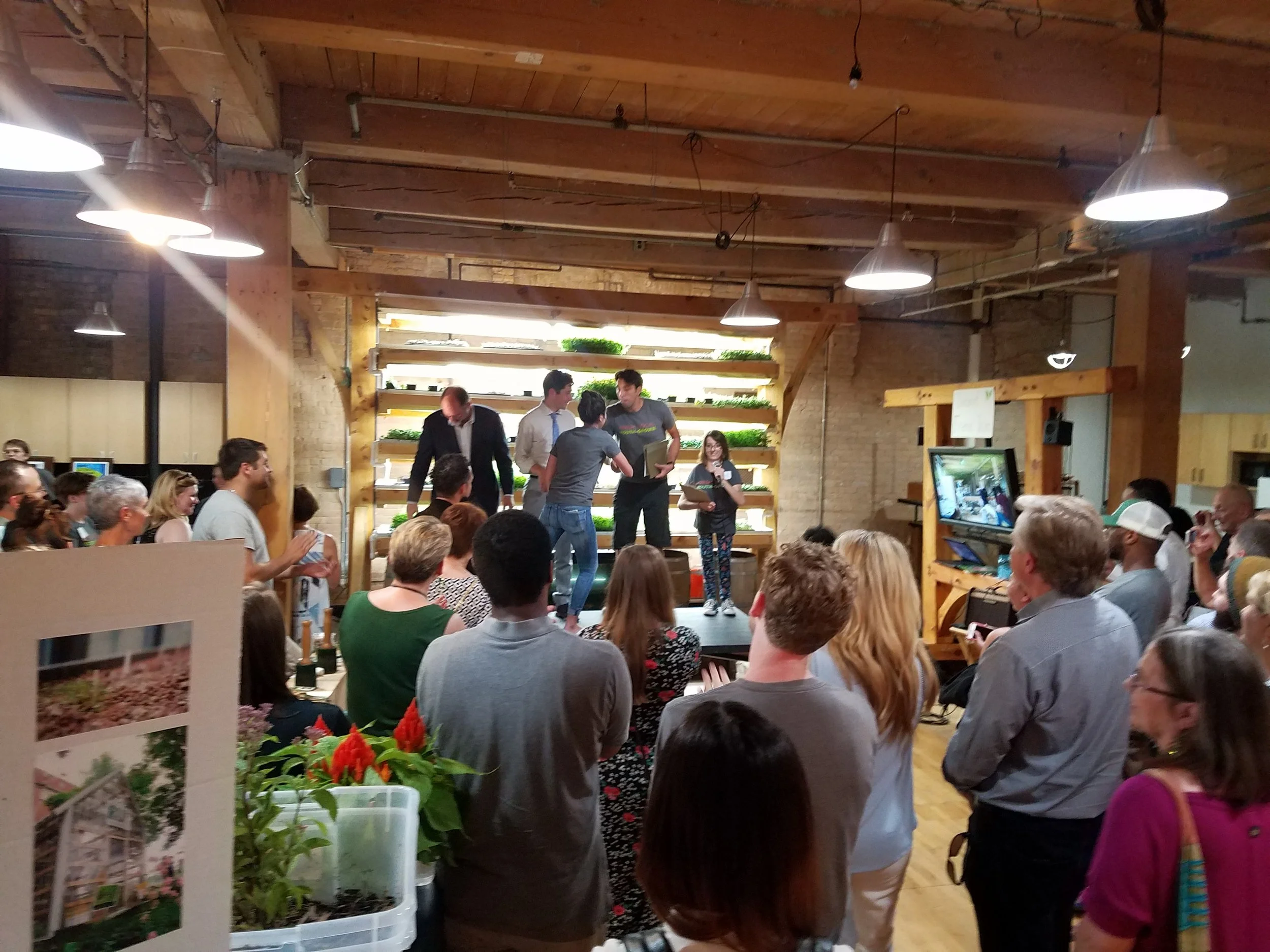 2018 interns receiving paid stipends, with Minneapolis Mayor Jacob Frey, in front of a youth-built timber frame aquaponics system at the Spark-Y Open House.