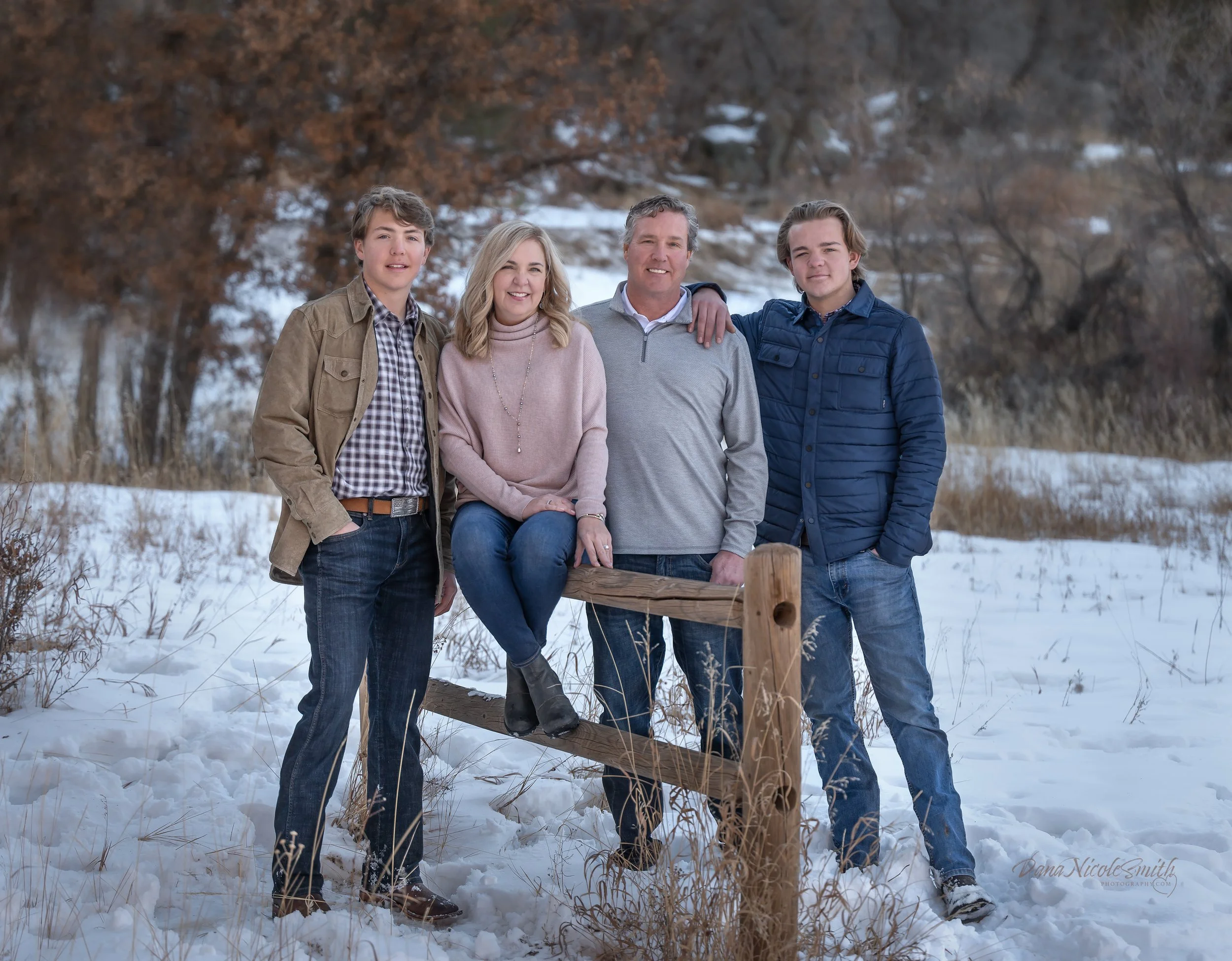 Family of five standing outdoors in a snowy field during winter.