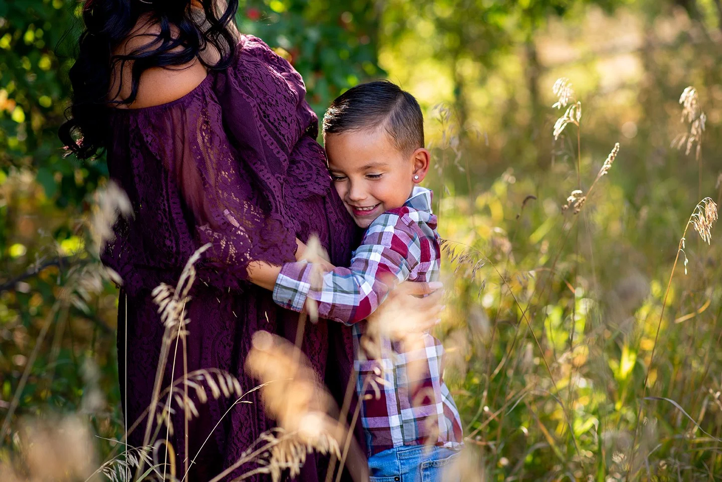 big brother holding moms pregnant belly in fall