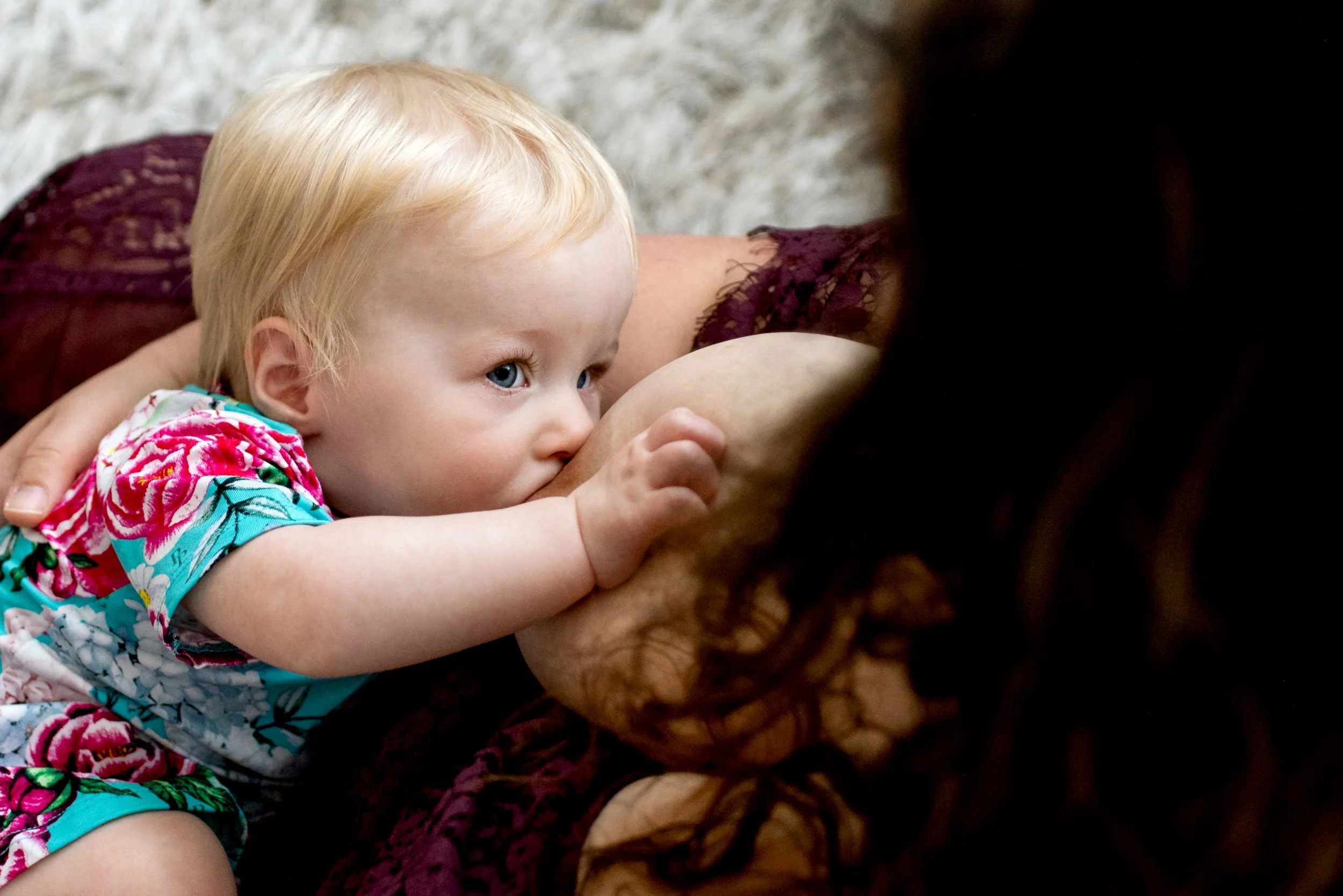 child nurses and looks at mom