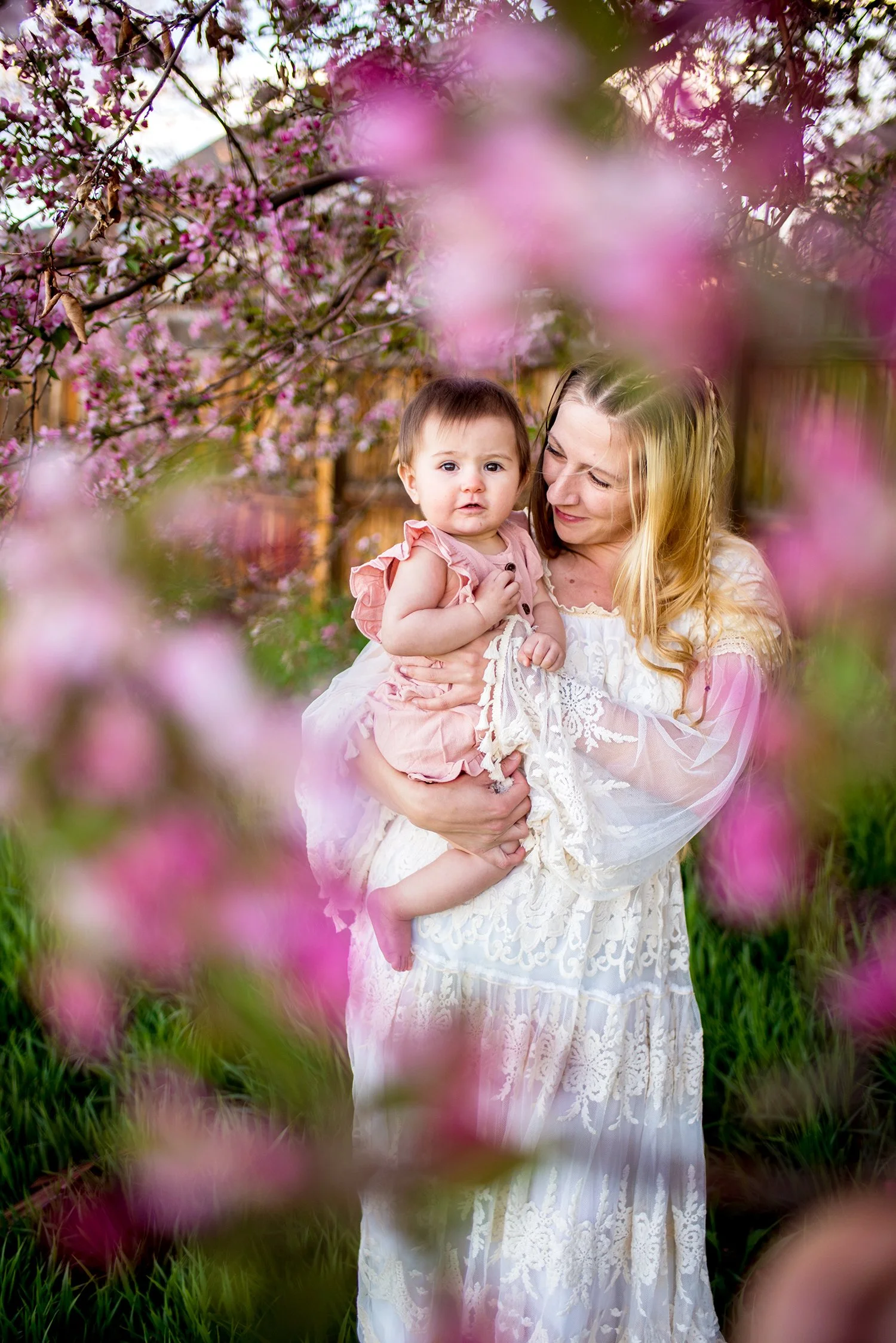 mom holding her daughter in pretty pink flowers outside