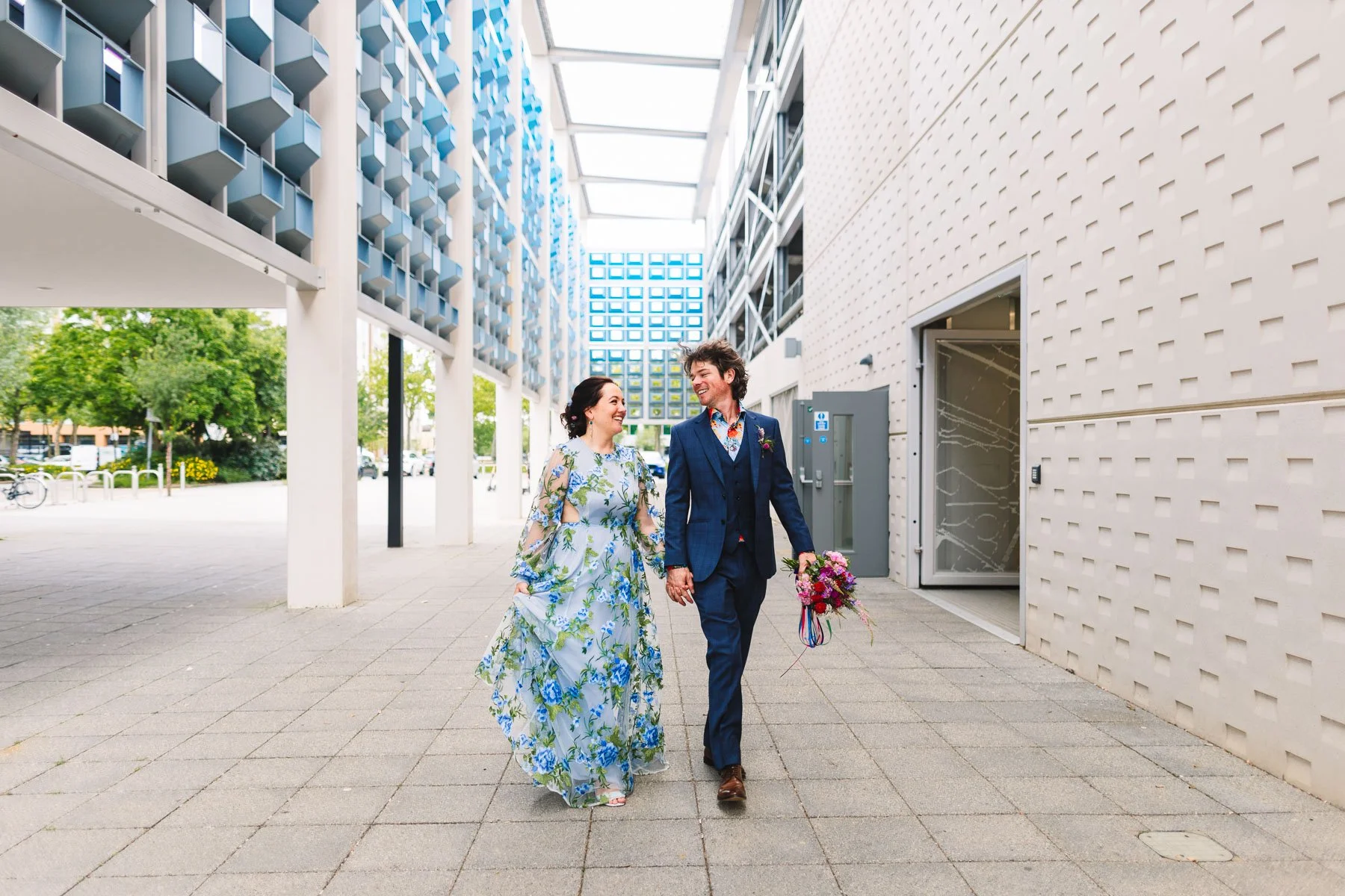 Newlyweds laughing together as they walk through Milton Keynes city centre on their wedding day