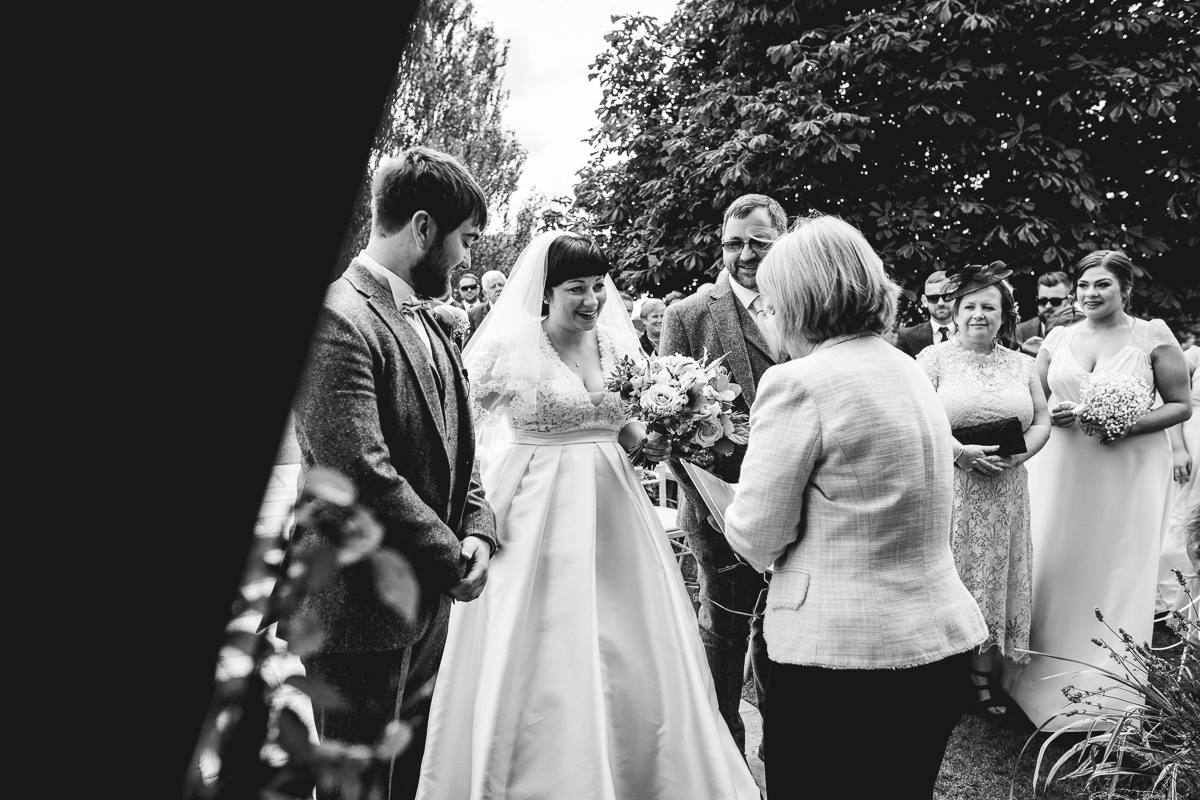 Bride and Groom stood at outdoor alter at fun summer wedding
