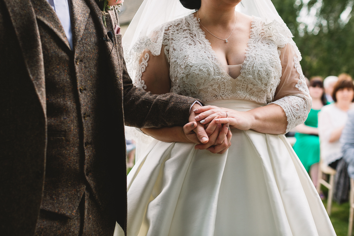 Bride and groom hold hands in natural candid moment during Hyde Barn Wedding ceremony