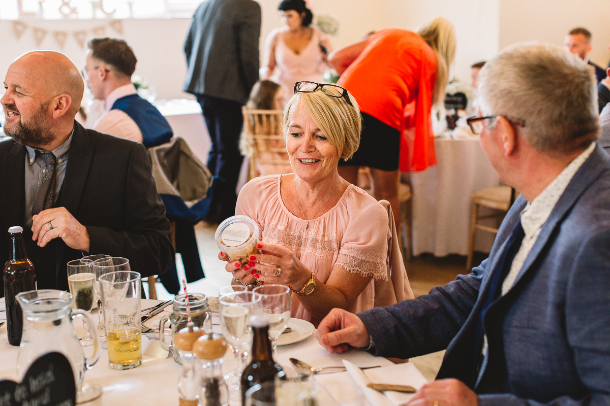 Woman in pink holds wedding favour inside the rustic Hyde Barn