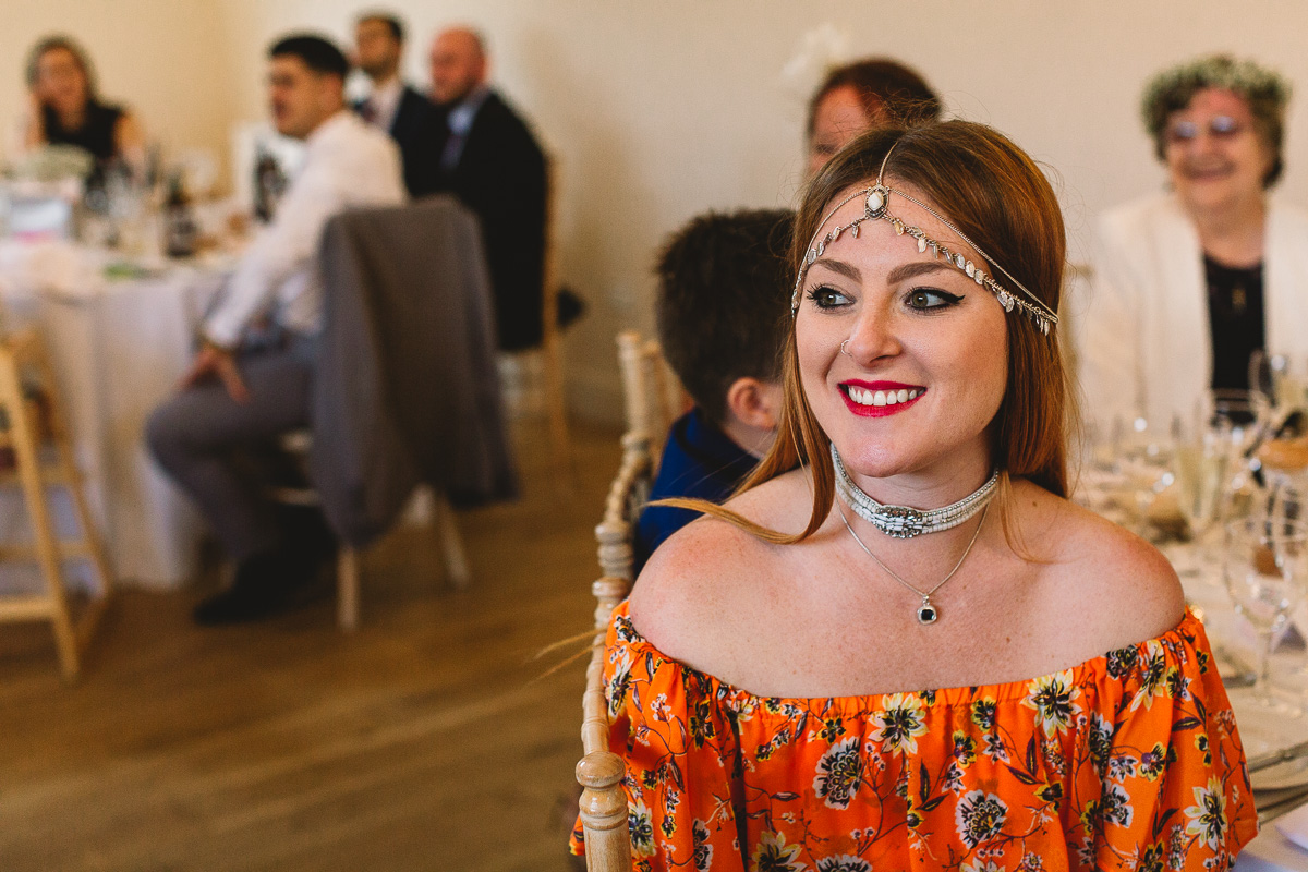 Alternative guest in hippy floral style dress smiles | Cotswolds Hyde Barn Wedding