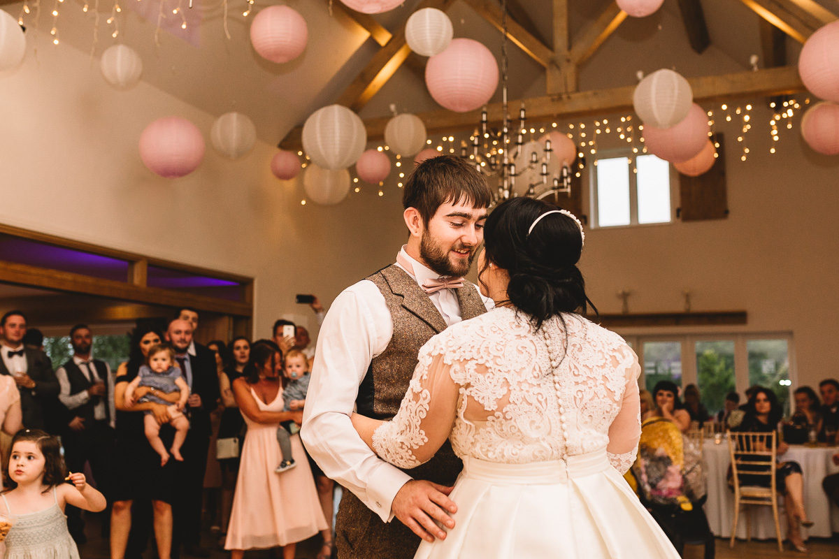 Groom looks at bride happily in first dance at Cotswolds wedding
