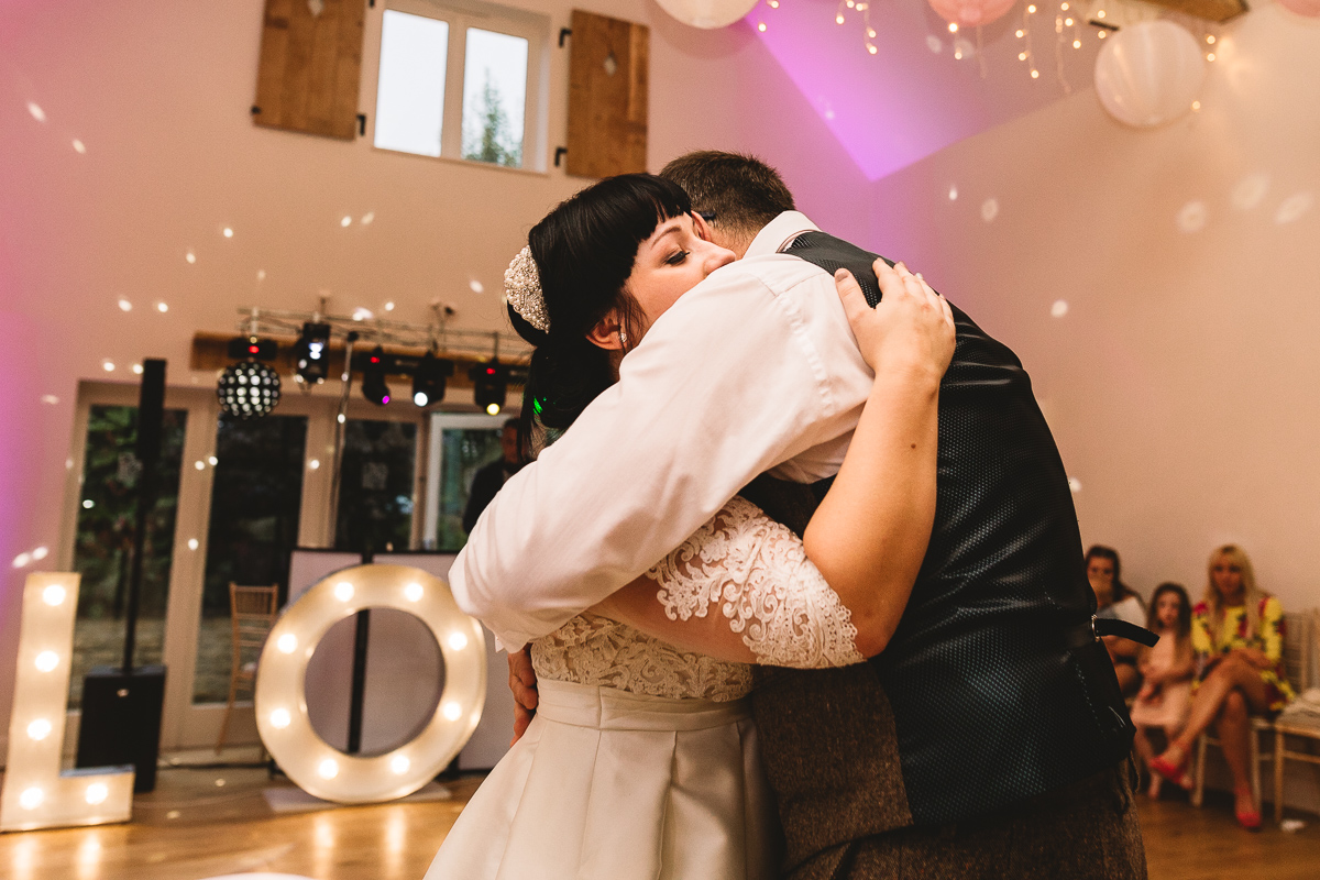 Photo of father and bride embrace in natural moment