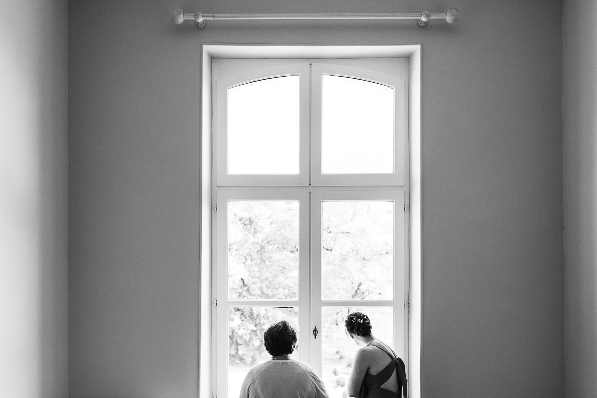 Documentary photo of bridal party looking out of chateau windows