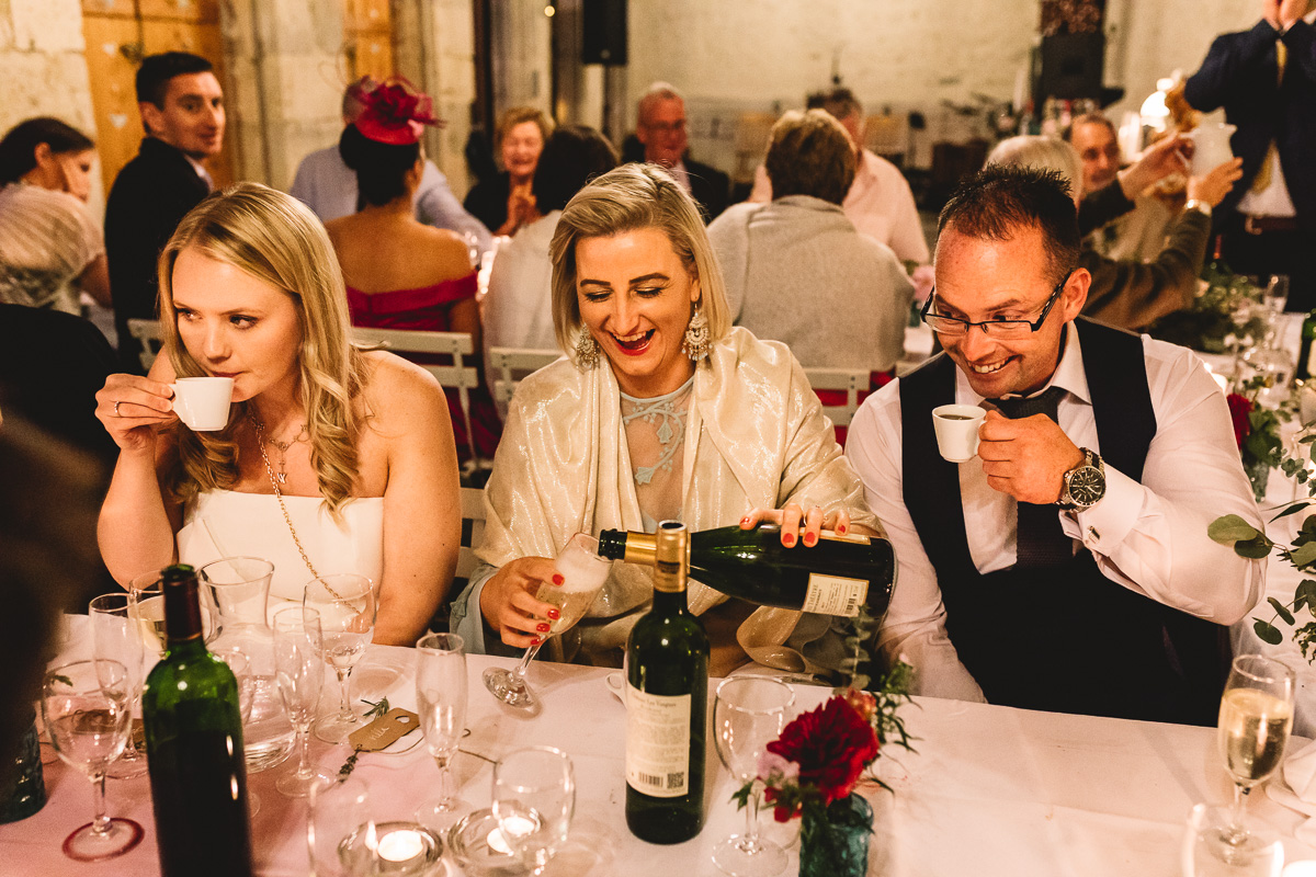 Fun guests drinking champagne at rustic france chateau wedding