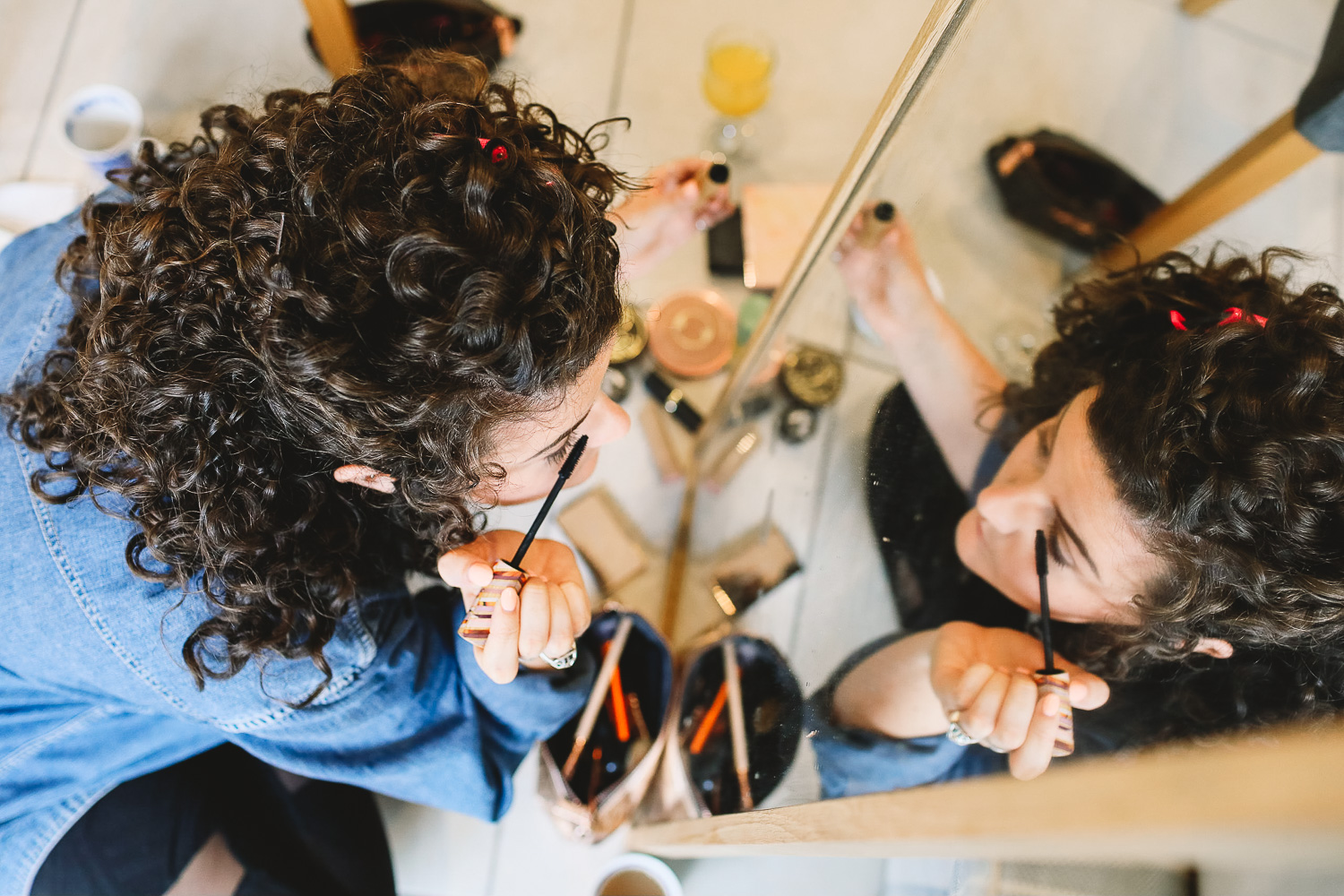 Photo of bridesmaid applying mascara in mirror at relaxed Sheffield wedding