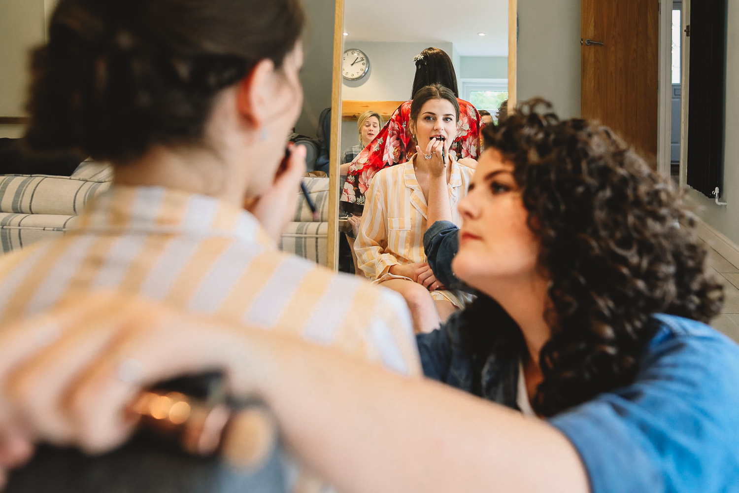 Bride in mirror having lipstick done by a friend during bridal prep in Sheffield
