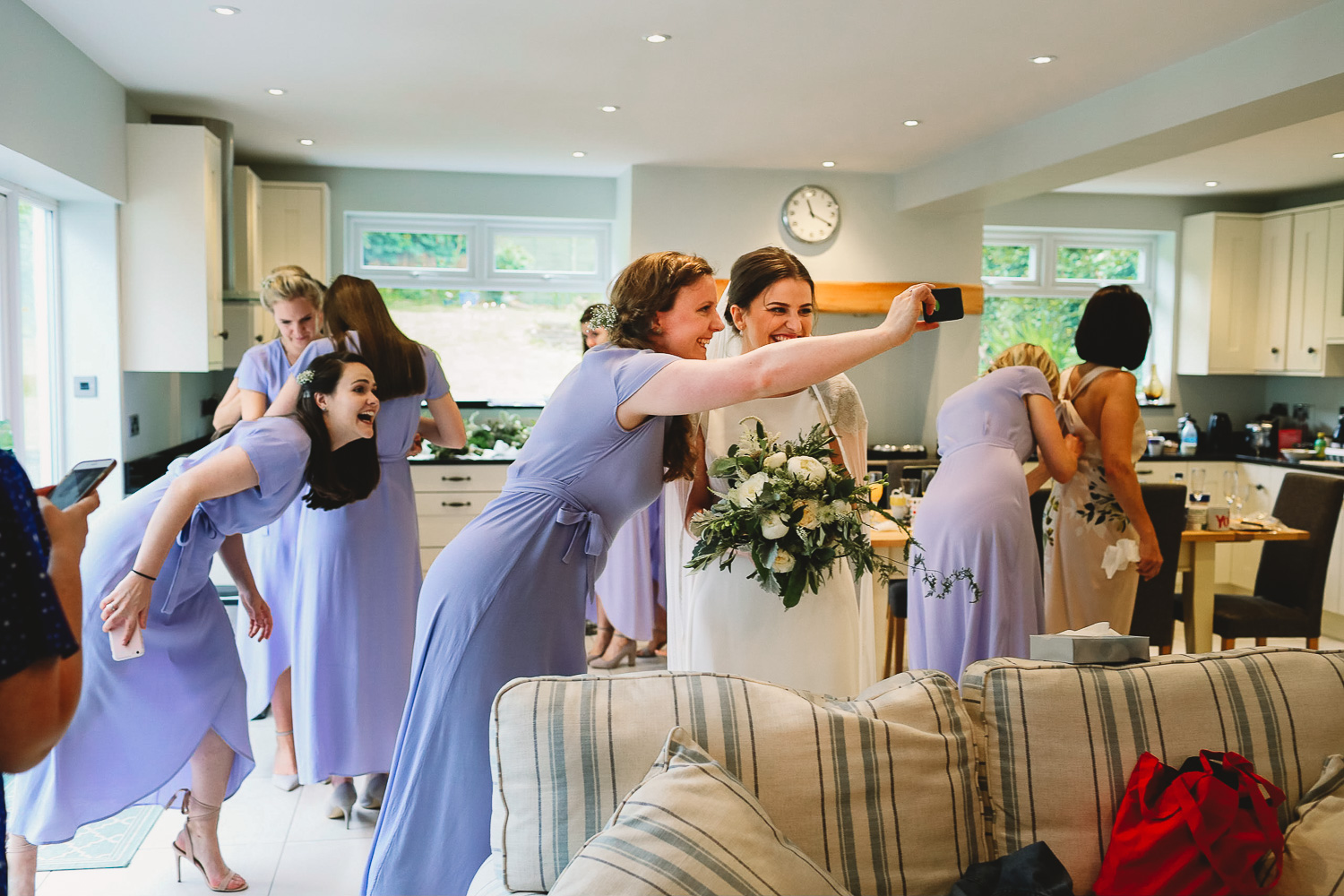Bridesmaid taking selfie with the bride and another bridesmaid photobombing and pulling funny face in the background at fun Sheffield wedding 