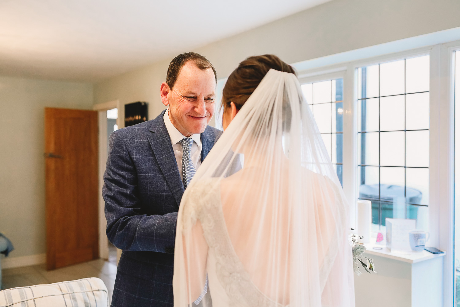 Dad approaches bride and holds her hands in his and has the happiest look on his face during bridal prep at relaxed Sheffield wedding