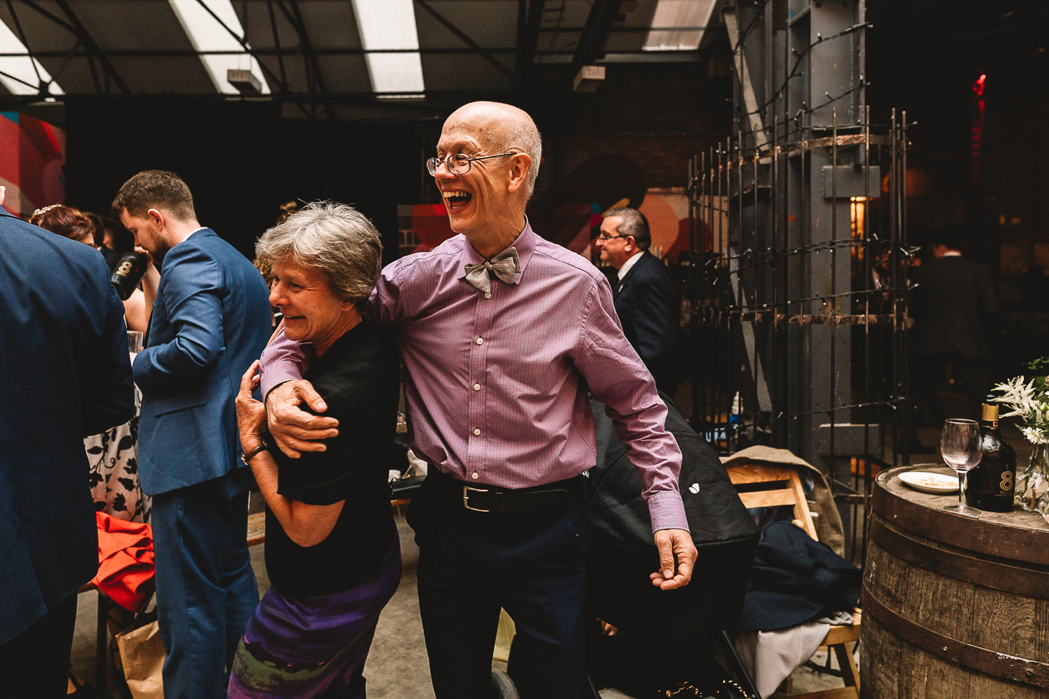 Two older wedding guests laughing and dancing with arms round one another on the dance floor at fun 92 Burton Road Wedding