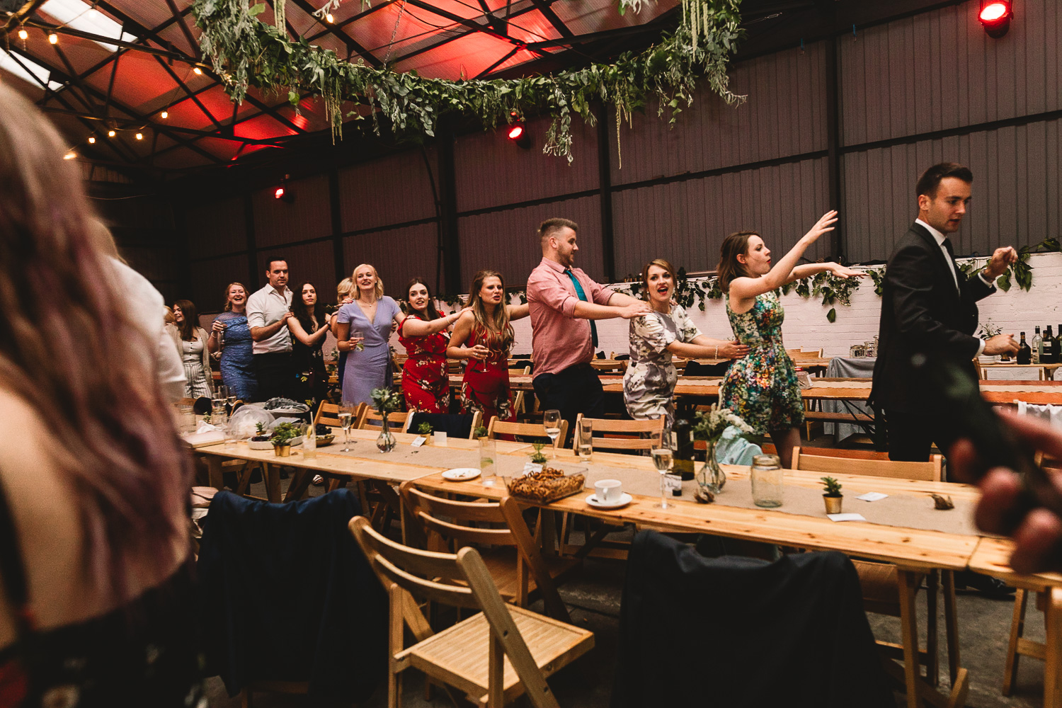Photo of guests having fun doing the conga around rustic tables in warehouse wedding venue 92 burton road in Sheffield
