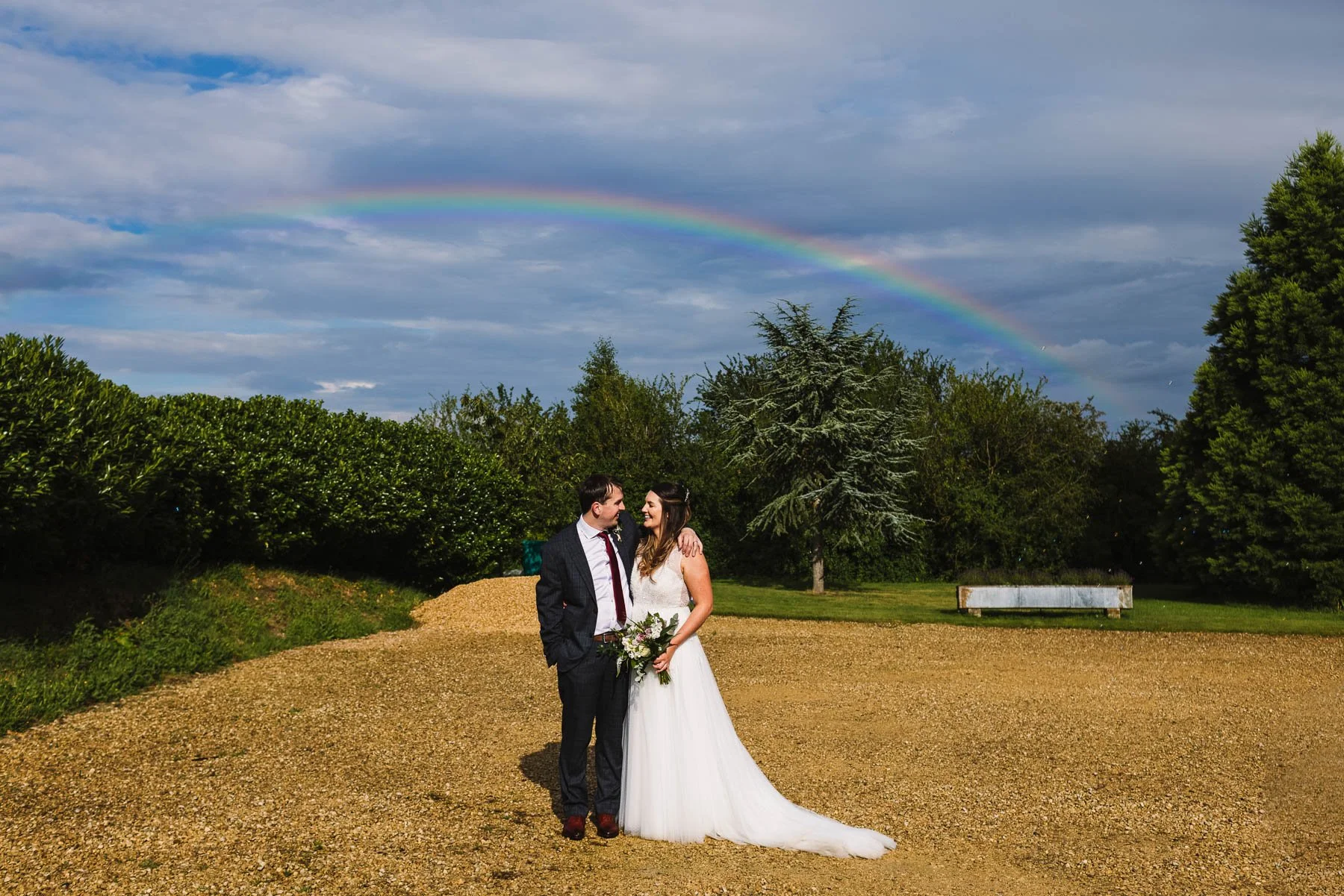 Bride and groom standing beneath a rainbow at Huntsmill Farm wedding venue