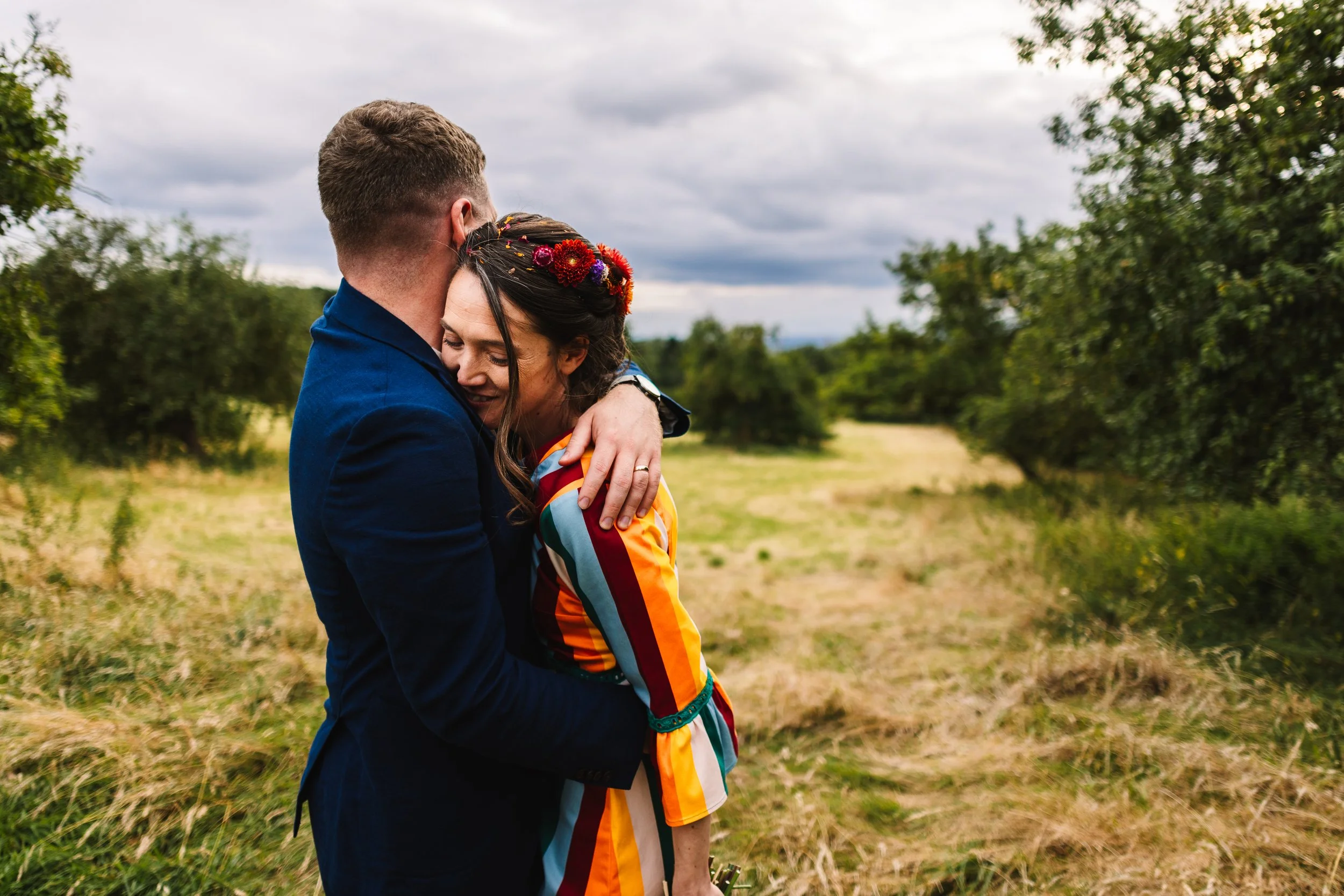 Newlyweds sharing a quiet hug in the meadow at The Firs on their wedding day