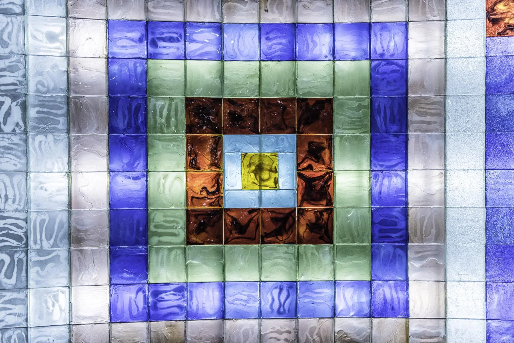 Colorful mosaic of glass tiles arranged in a pattern with concentric squares of yellow, blue, red, green, and white colors.