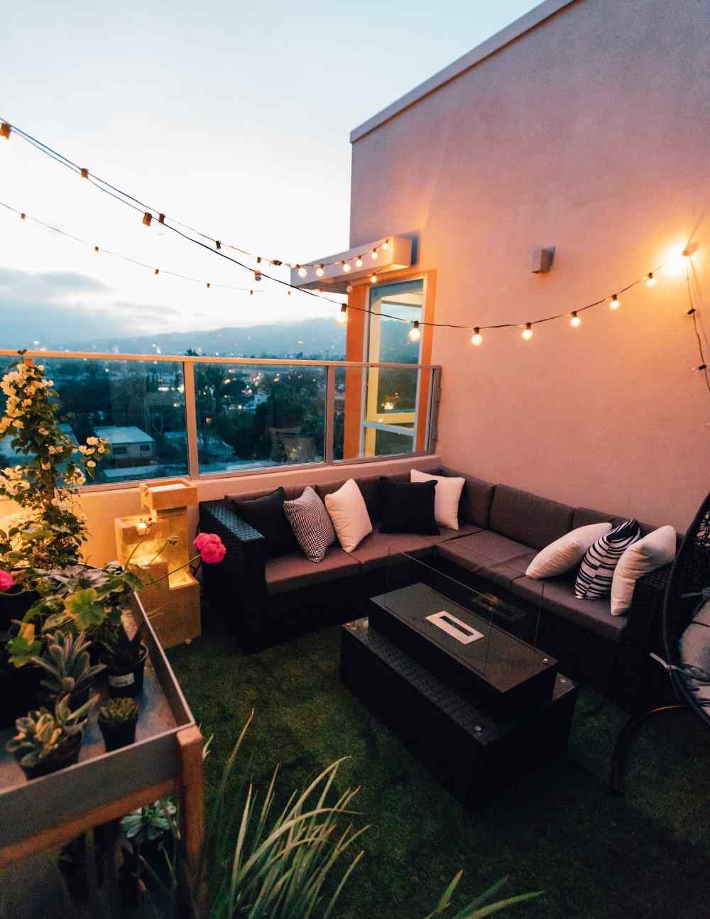 outdoor patio balcony with plants, lighting, and comfortable furniture