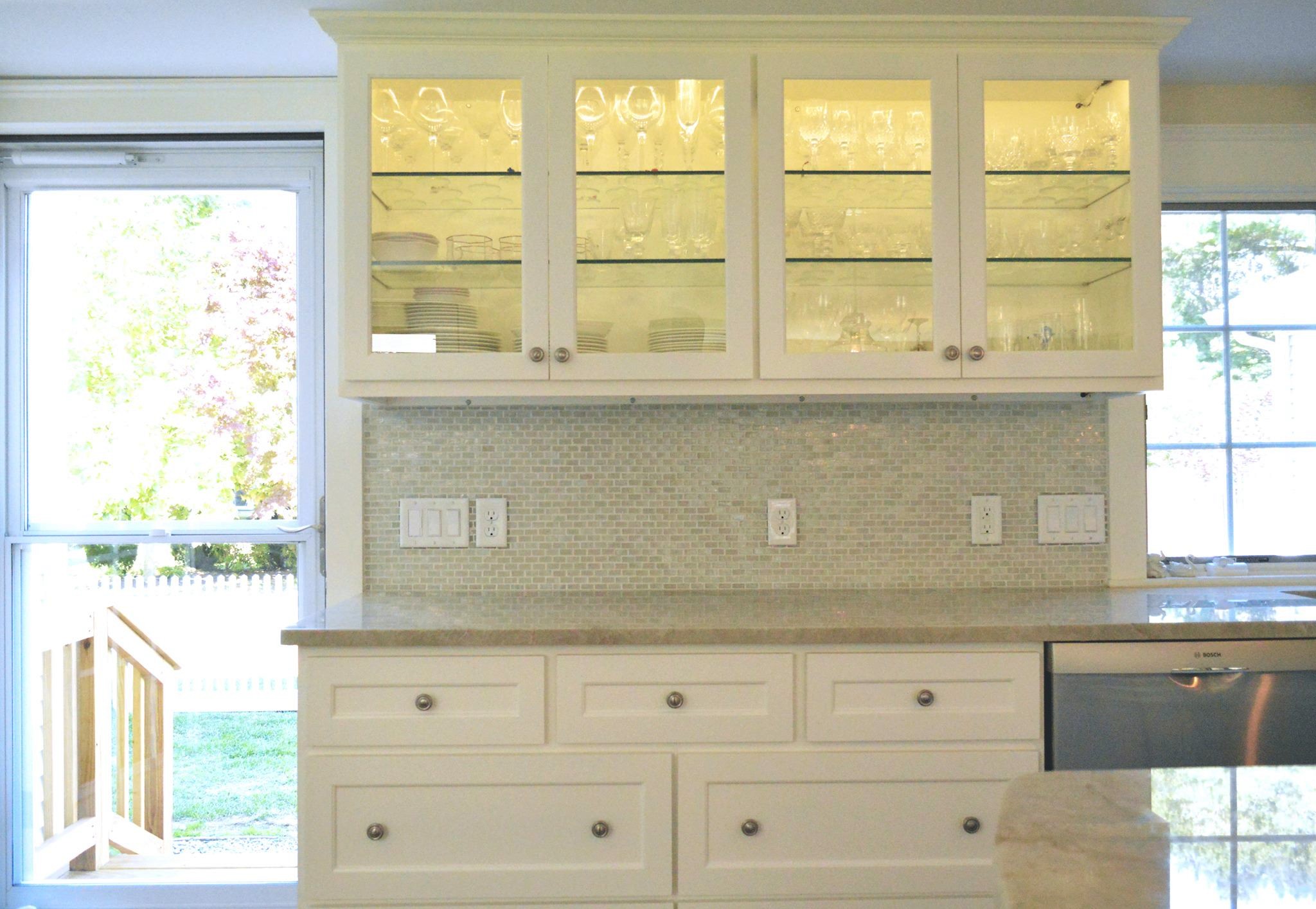 Glass cabinets with interior lighting showcase the client's stemware collection.jpg