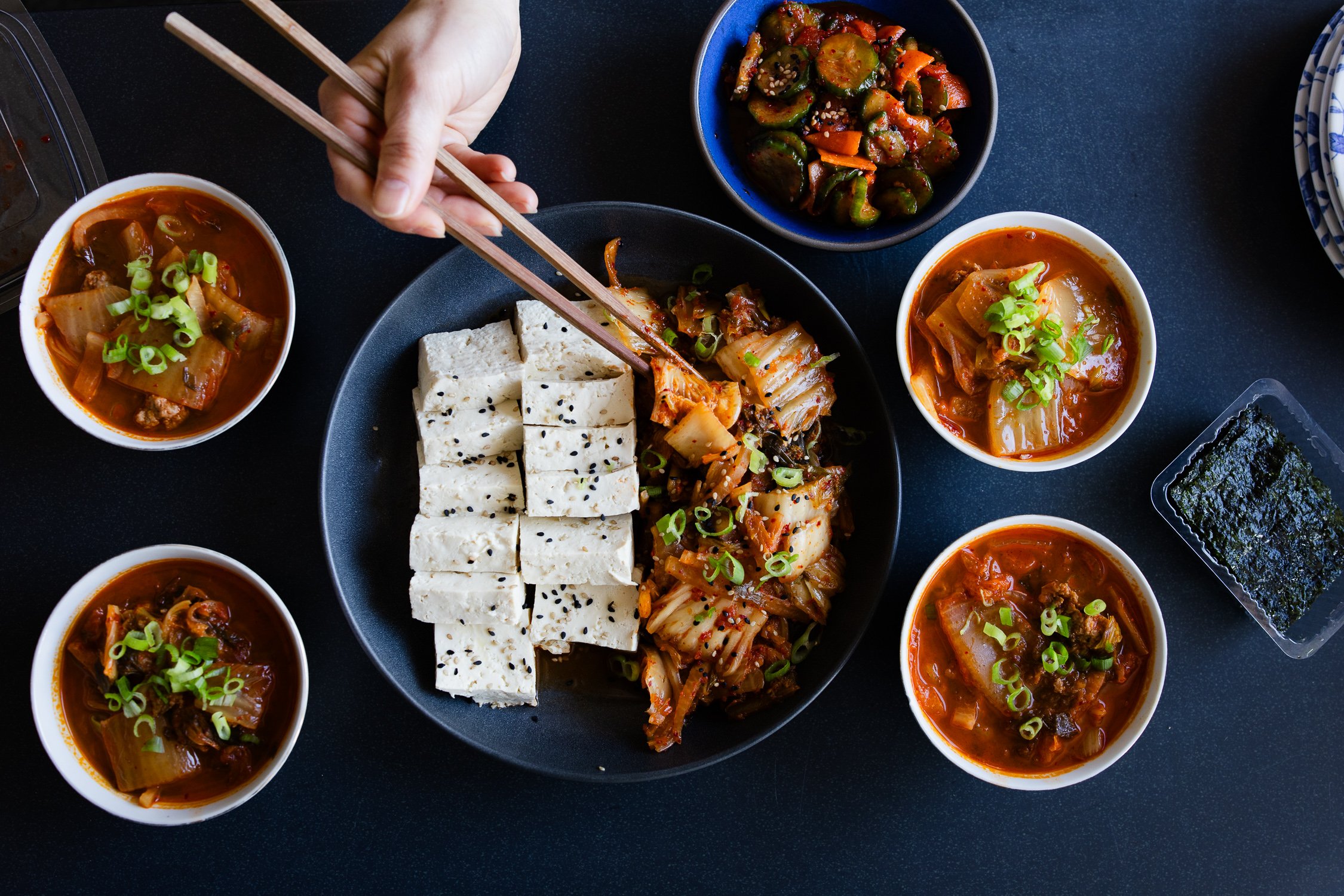 Bowl of kimchi and tofu with chopsticks lifting a piece, photographed for a San Francisco kimchi maker’s brand photography session