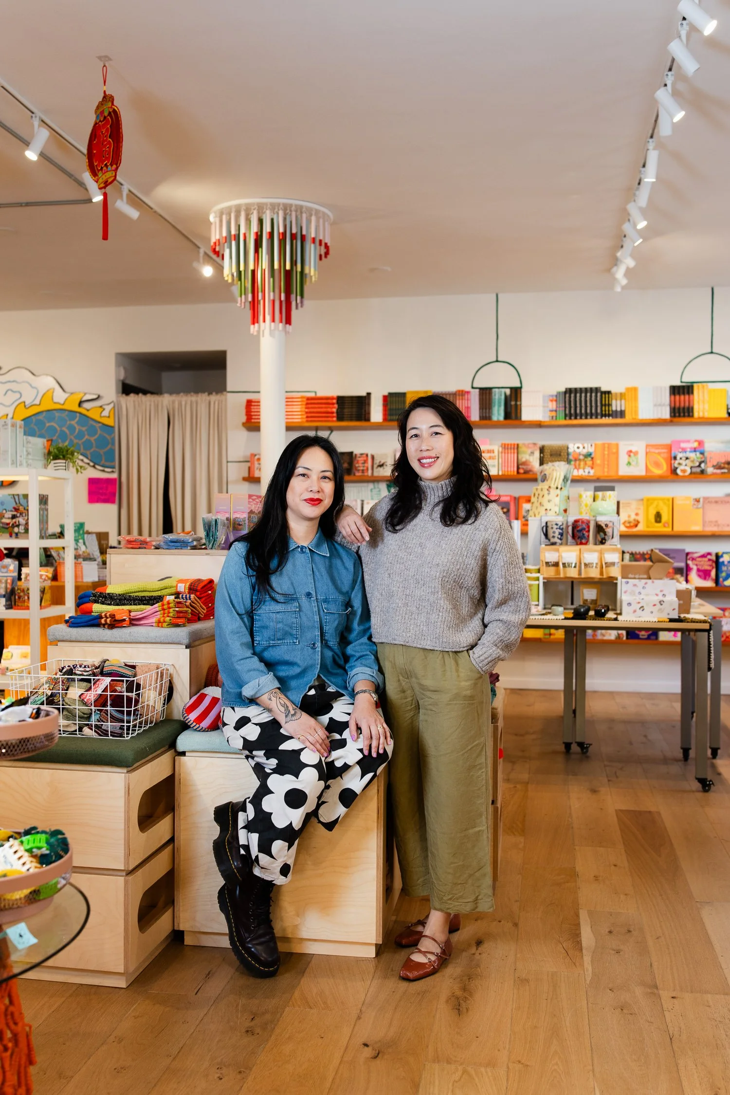 San Francisco brand photography of the owners of On Waverly inside their gift shop, one seated and one standing, surrounded by books, artwork, and curated goods.