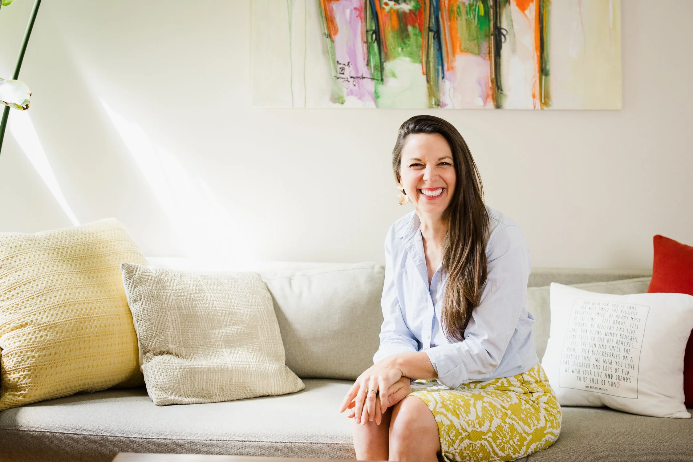 Coach sitting on her couch smiling during a brand photography session, showing a warm and approachable client experience
