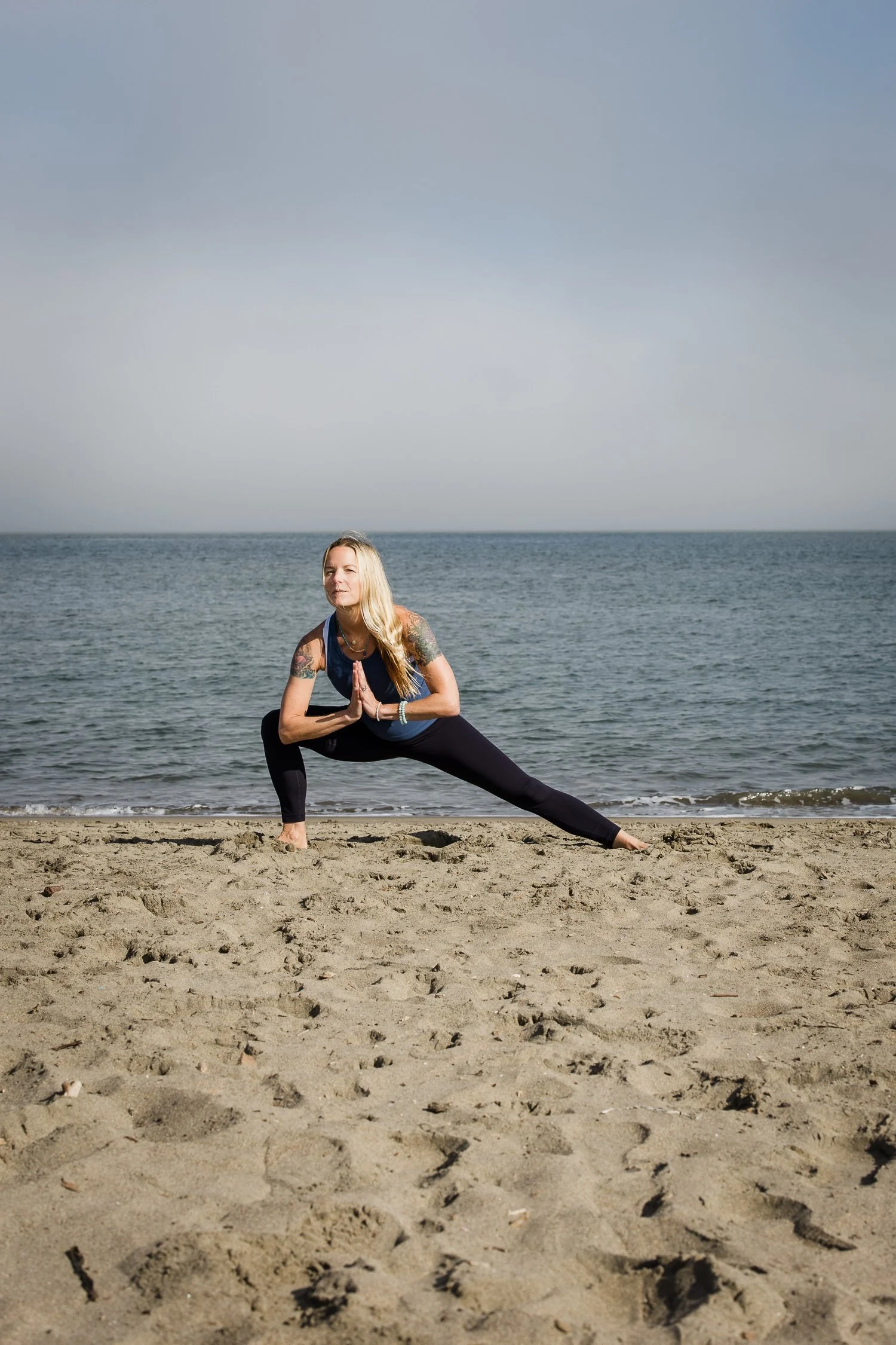 San Francisco brand photography of a yoga teacher practicing on a beach in a low lunge pose near the ocean.