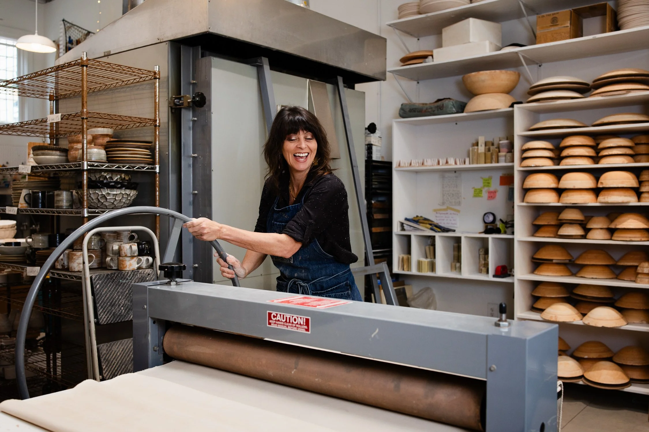 Ceramic artist MaryMar of MMClay flattening clay slab, process from San Francisco brand photography session