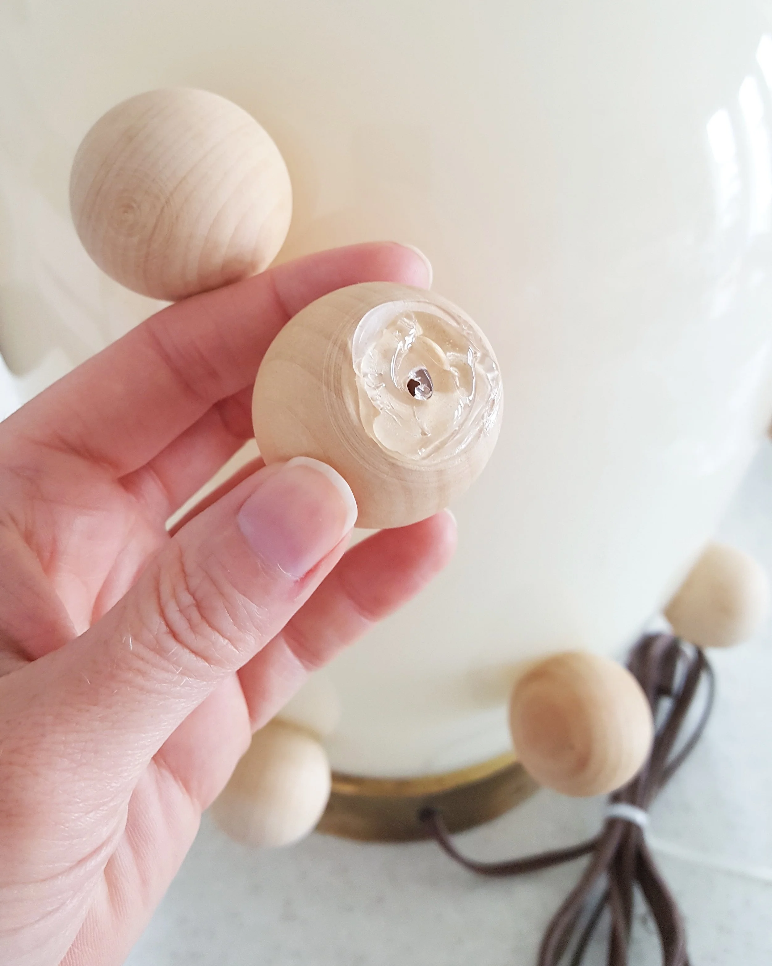 Step 3: Glue wood knobs onto lamp base using a glue gun. I placed wood knobs along the seams first and then eye-balled placement for the rest in an alternating pattern. A few fell off after a few hours so I reattached them using Gorilla Glue.