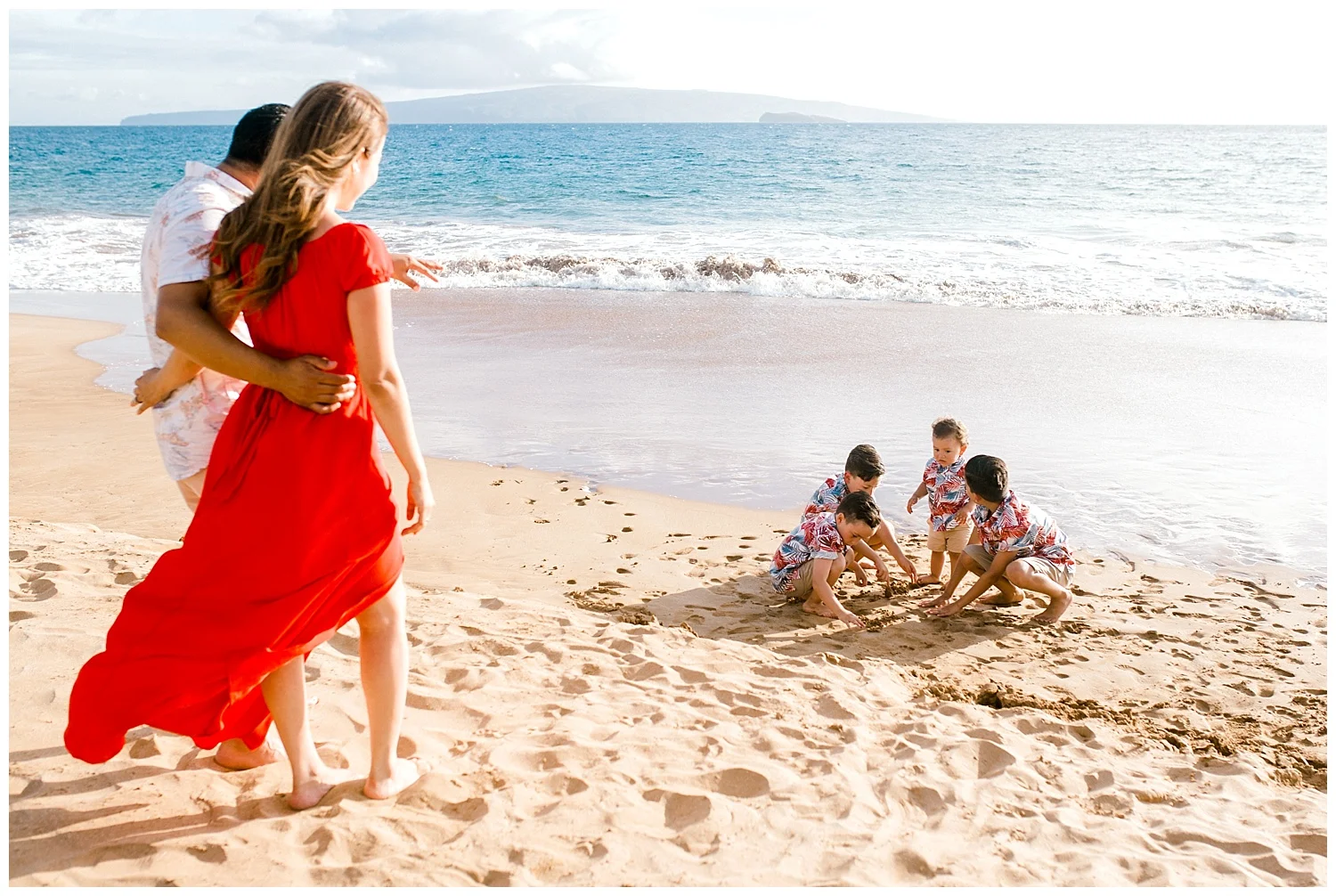 Mother and father watching children play in the sand on a Maui beach