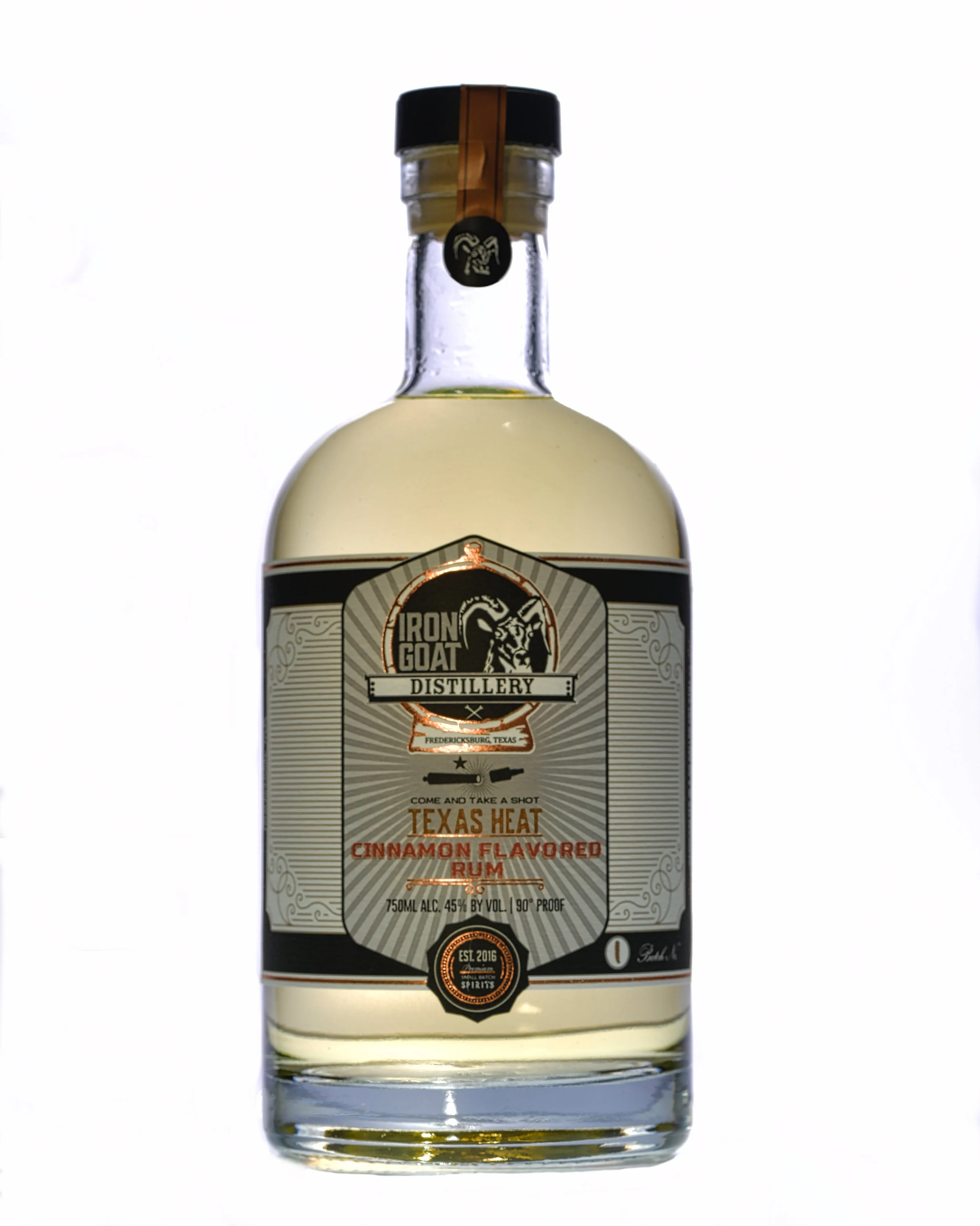 A clear glass bottle of Iron Goat Distillery Texas Heat Cinnamon Flavored Rum with a black cap, a black and copper sticker, and a beige label with black text and decorative elements, against a plain white background.