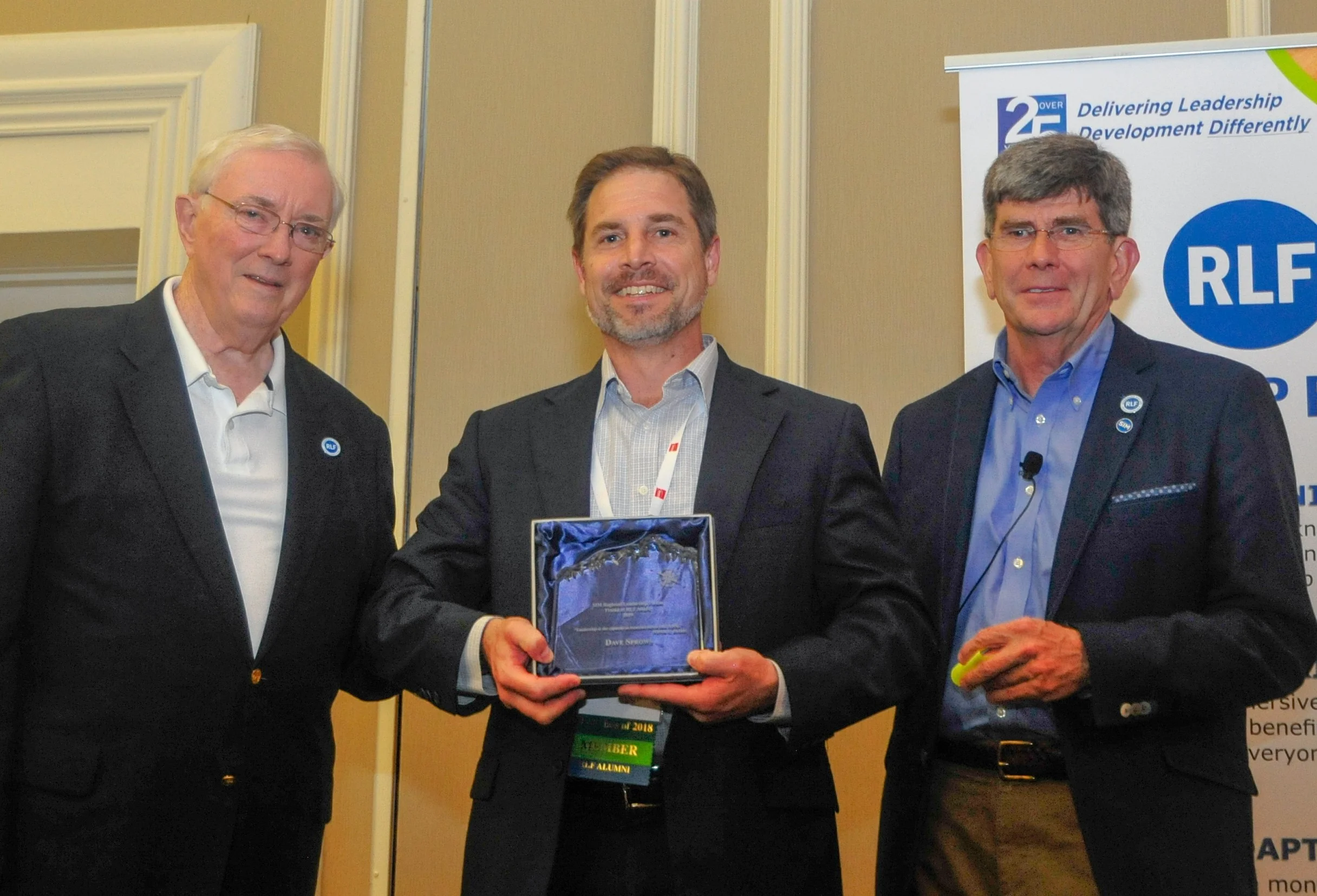 Two “Friend of RLF” awards were presented on May 15, 2019 during SIM Connect Live. Above, Northeast RLF facilitators Bart Bolton (left) and Kevin Ryan (right) present a “Friend of RLF” award for Dave Sprows of Wellington Management — accepted on Dave’s behalf by his Wellington colleague Phil Hattwick. Pat Randall of Kforce also was presented with a “Friend of RLF” award during the event.