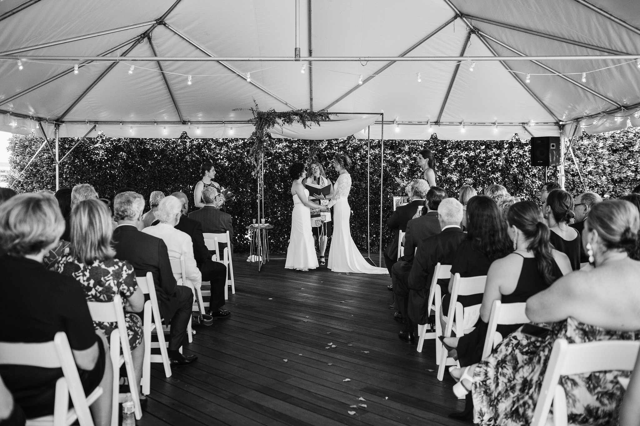 Engaged couple taking making wedding vows during ceremony, with attendees seated in foreground