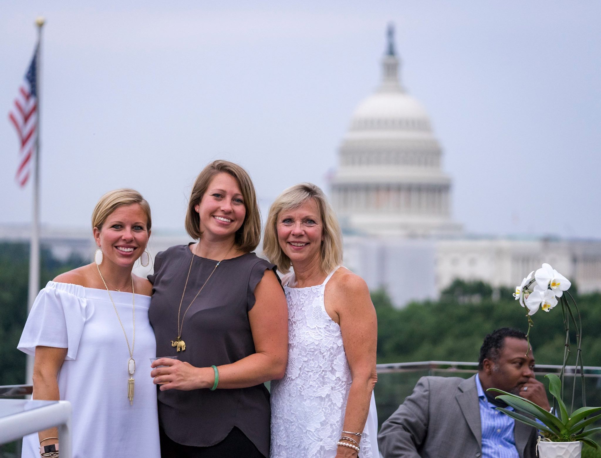 Three women posing for group photo, with Capitol building in background