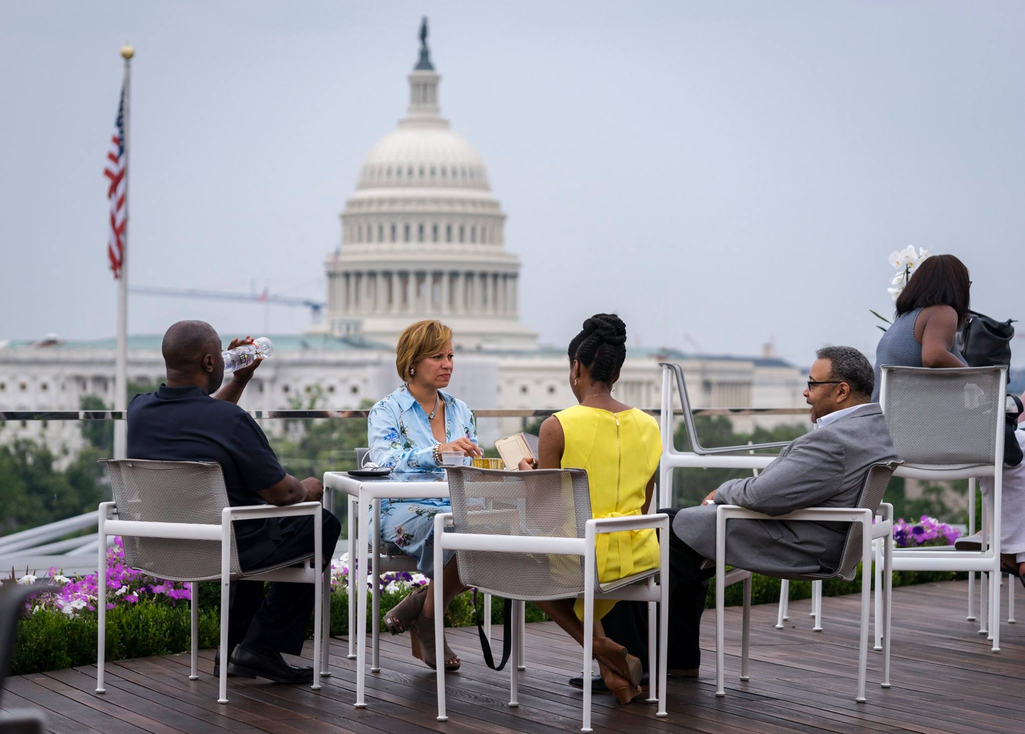 Group sitting at patio table on rooftop deck, with Capitol building in the background